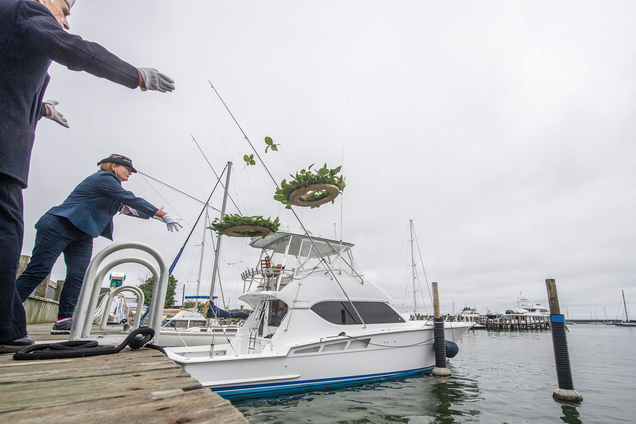 Wreaths are tossed into the water to remember lost seamen during a ceremony in Marine Park during the 2021 Memorial Day parade and ceremonies in Sag Harbor on Monday.    MICHAEL HELLER