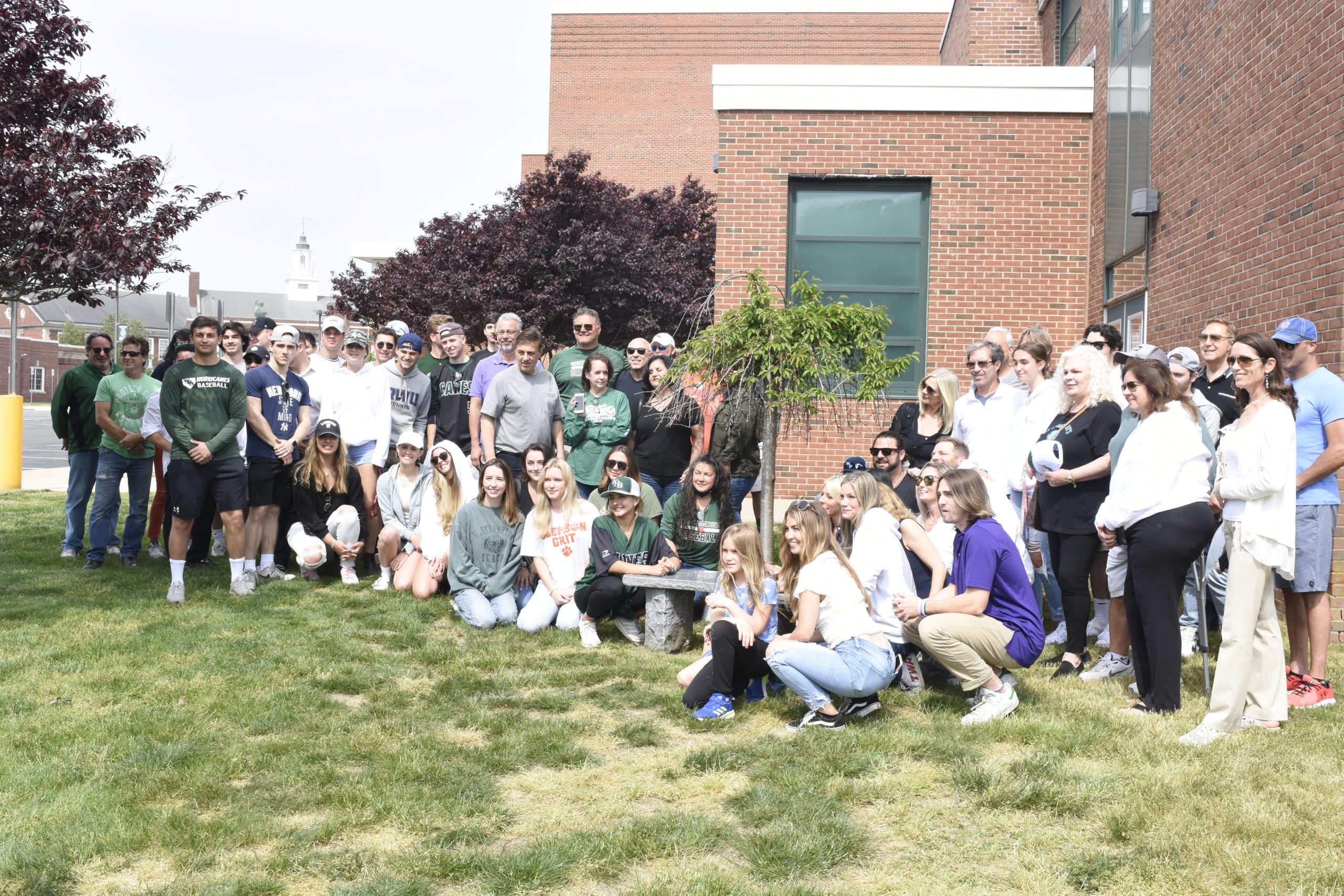 Family and friends gather around Gianni Mongelluzzo's plaque and tree at Westhampton Beach High School.