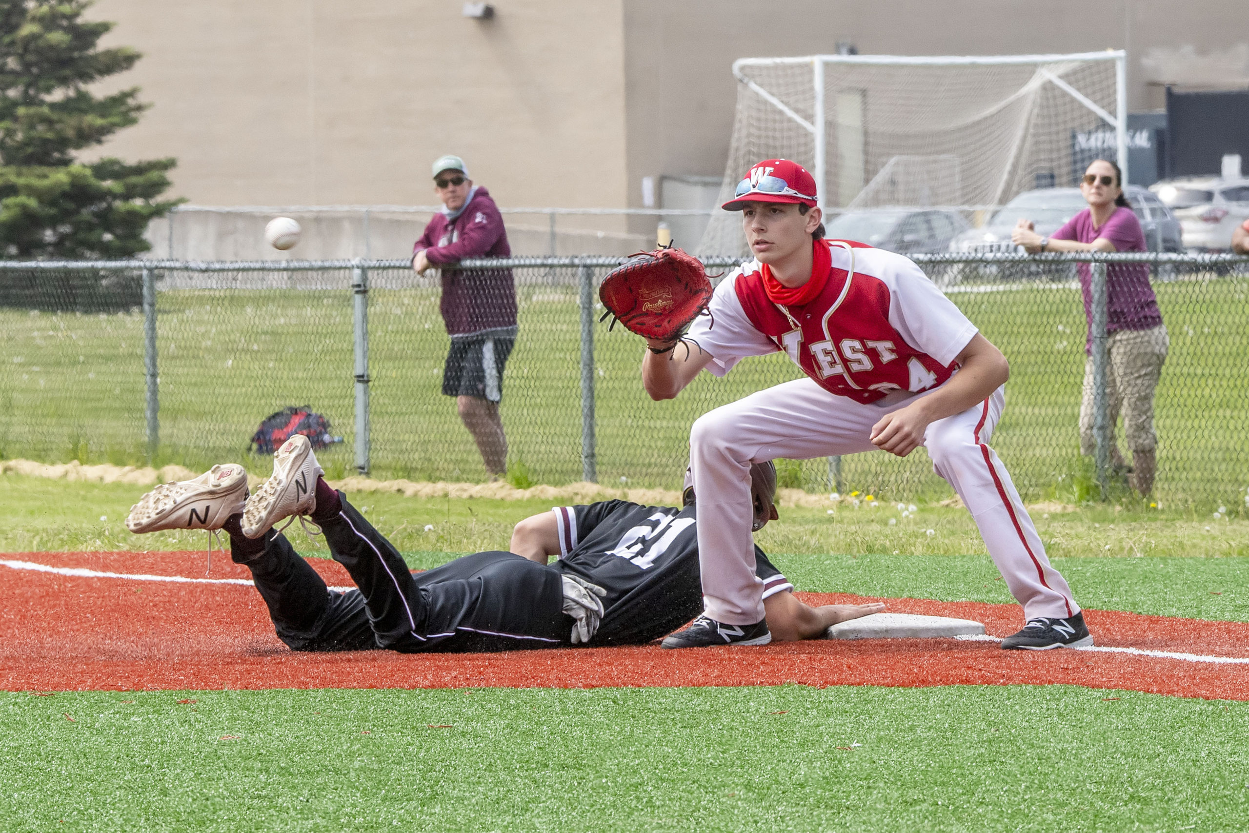 East Hampton senior Drew Salamy slides back to first base safely following a pick-off play.