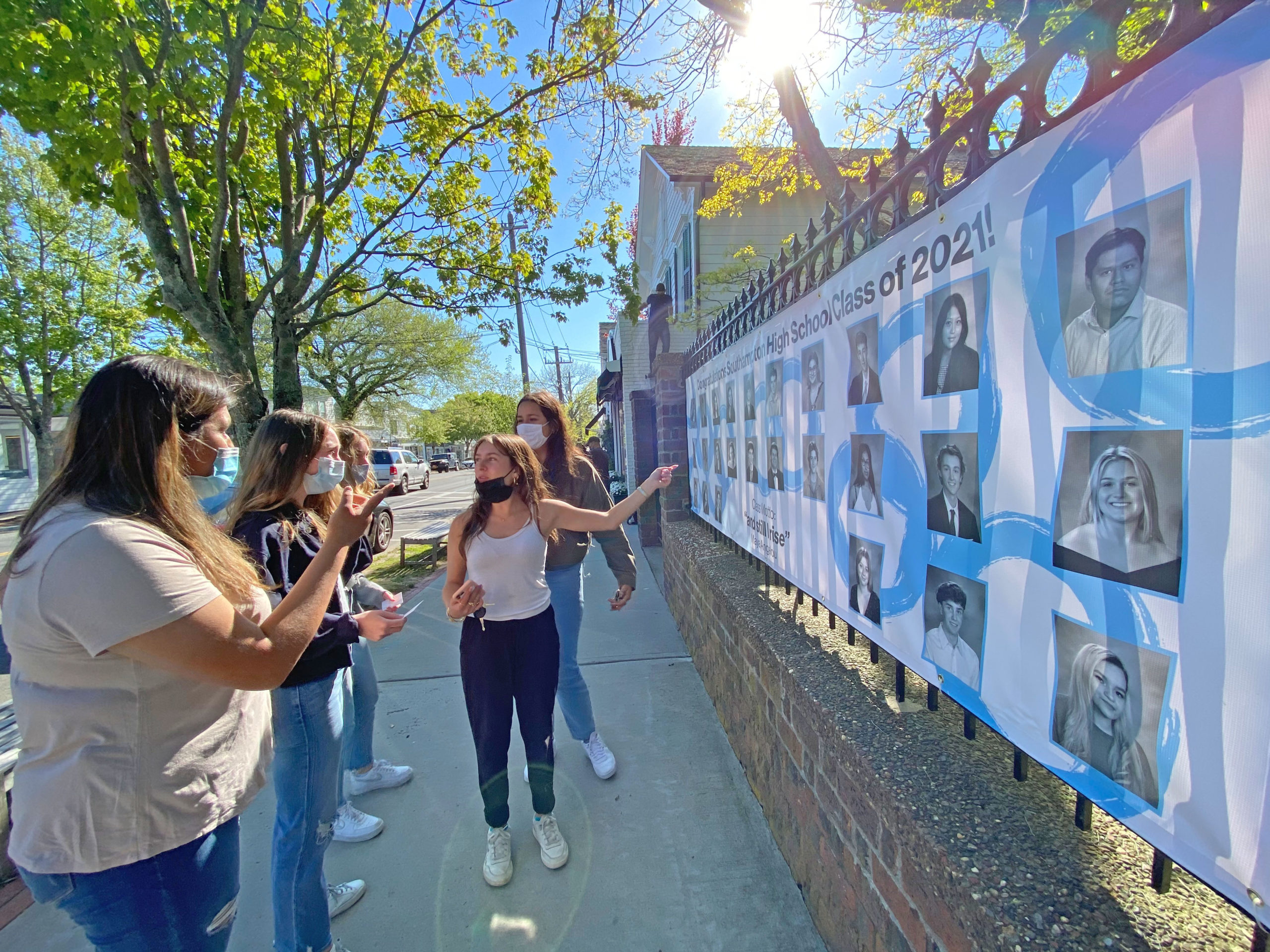 Southampton High School  Seniors look for their photo on banners in front of the Southampton Arts Center on Friday afternoon. The Southampton Arts Center will unveiled the banner honoring Southampton High School graduating seniors as part of a second annual event to acknowledge the accomplishments and resilience of the students. Beginning in 2020 in the height of the COVID-19 pandemic, the banner was conceived as a way to honor Southampton graduates, featuring photos of all of the graduating seniors and the class motto, “And still I rise.”     DANA SHAW