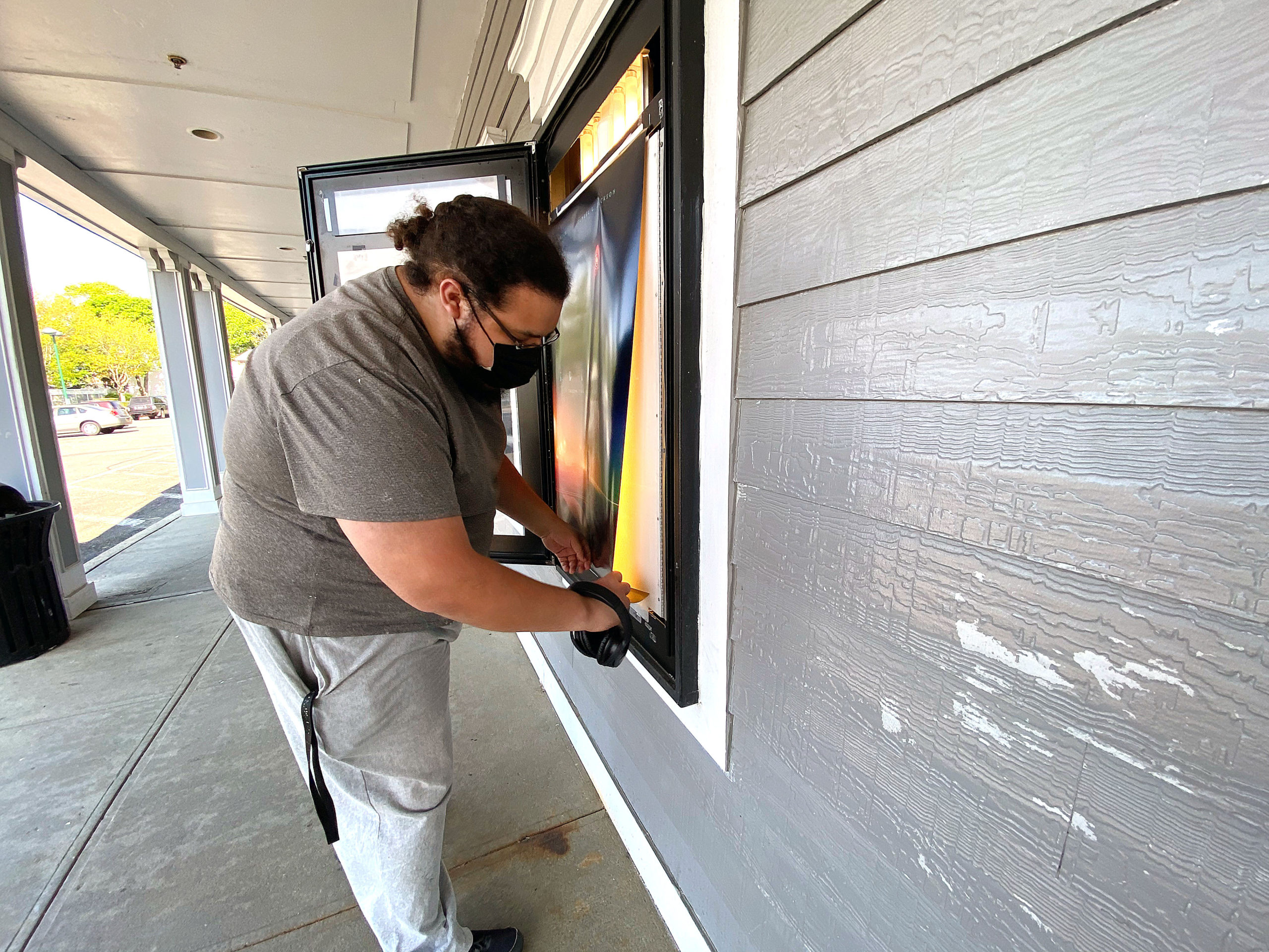 An employee replaces the now showing posters at the Hampton Bays United Artists movie theater on Monday. The theater is set to reopen May 21 under the company’s “CinemaSafe” COVID-19 guidelines.  DANA SHAW