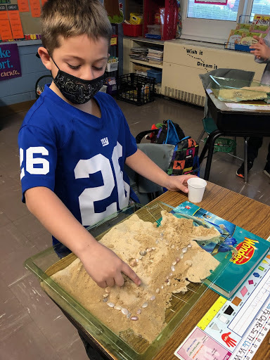 As part of a science unit on erosion, Westhampton Beach Elementary School second graders created their own “beach” to simulate the erosion process. For the experiment, the students placed sand and small rocks in a plastic container and then slowly poured water over them to see what happens to the sand.