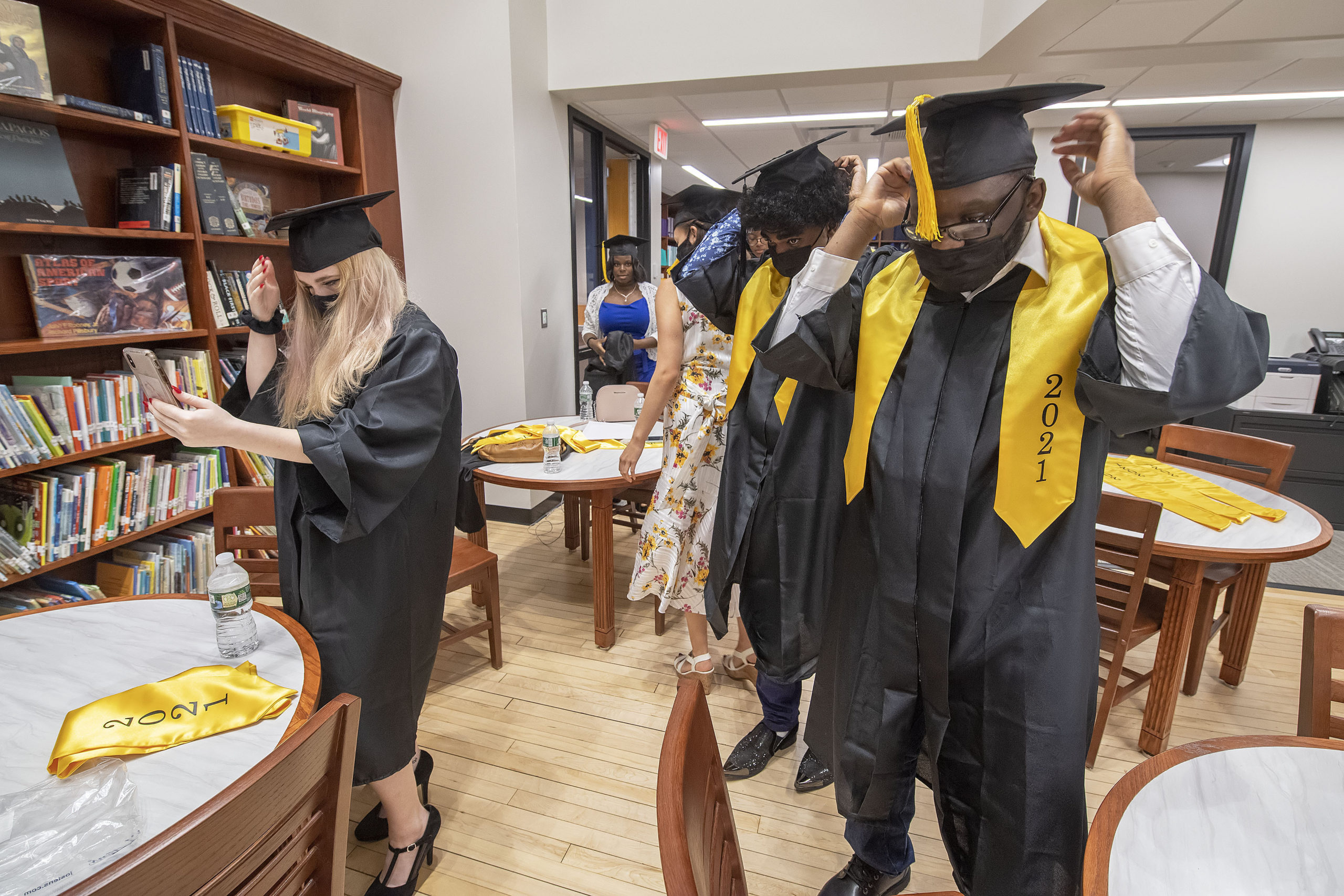 The seniors prep themselves and get dressed as they wait in the school's new library prior to the start of their 2021 commencement ceremony on Saturday.     MICHAEL HELLER