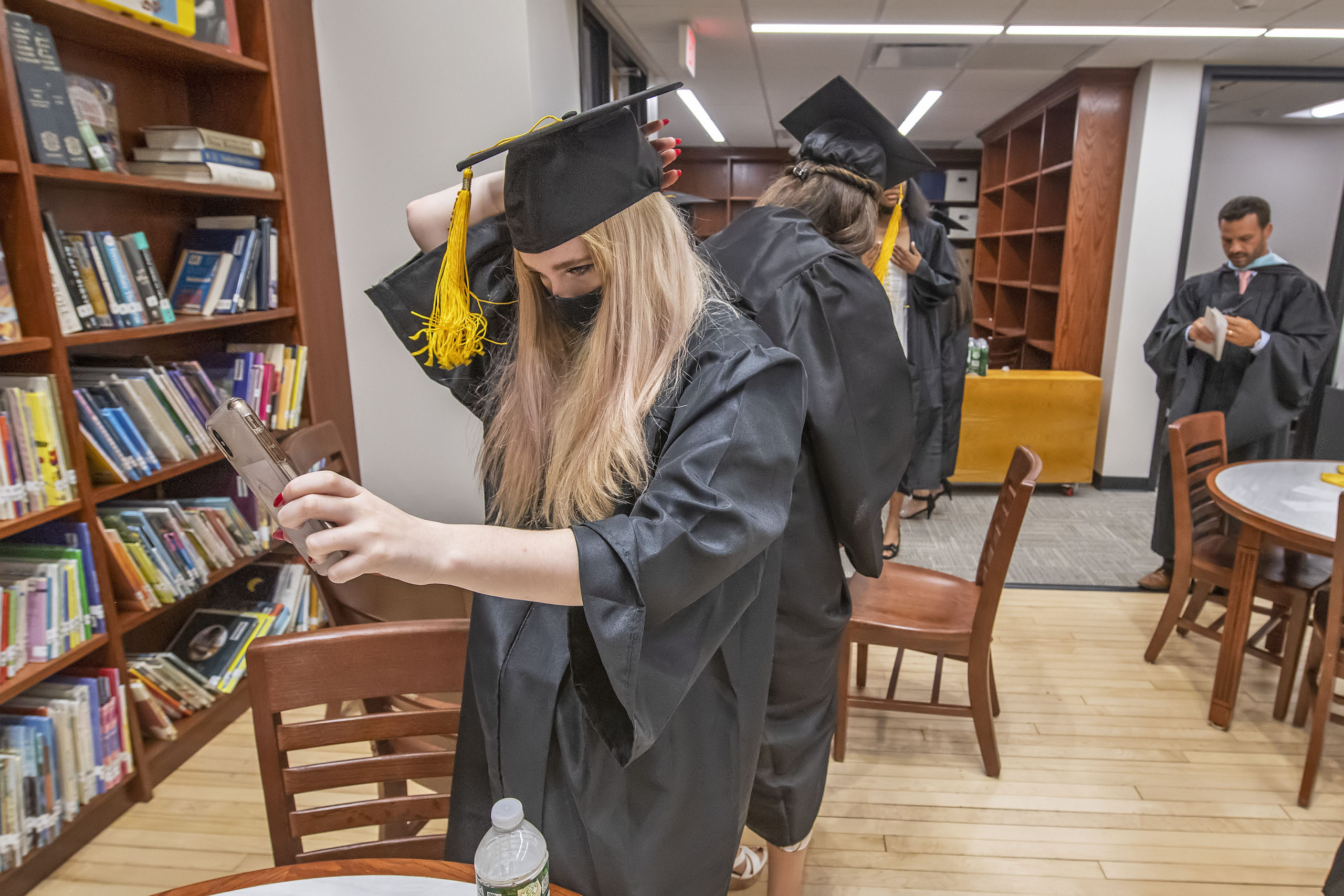 Bridgehampton School senior Maile Buccigross uses her phone as a mirror as she adjusts her cap in the school's new library prior to the start of their 2021 commencement ceremony on Saturday.     MICHAEL HELLER