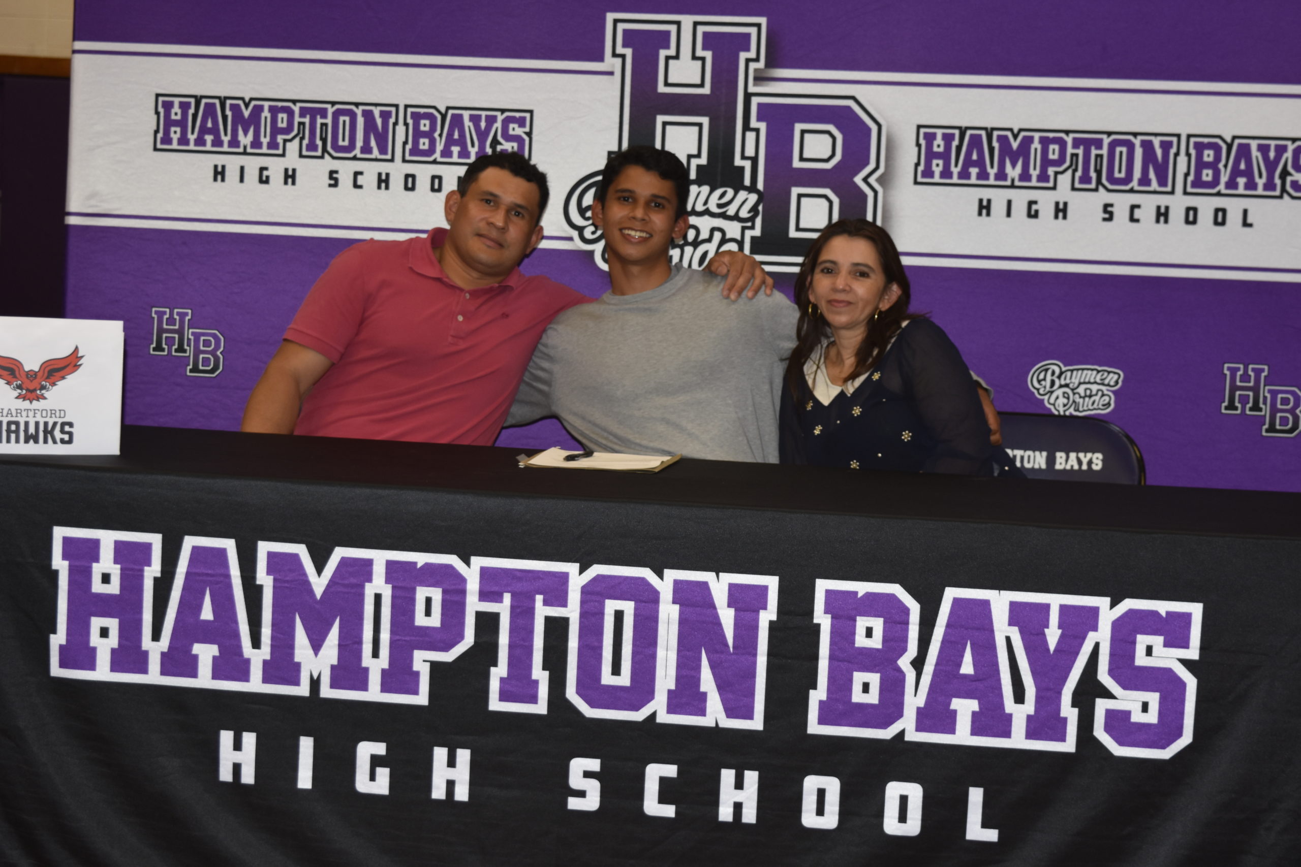 Darwin Fernandez, with his parents, Darwin and Cynthia Deras, after signing his letter of intent to run track at the University of Hartford.