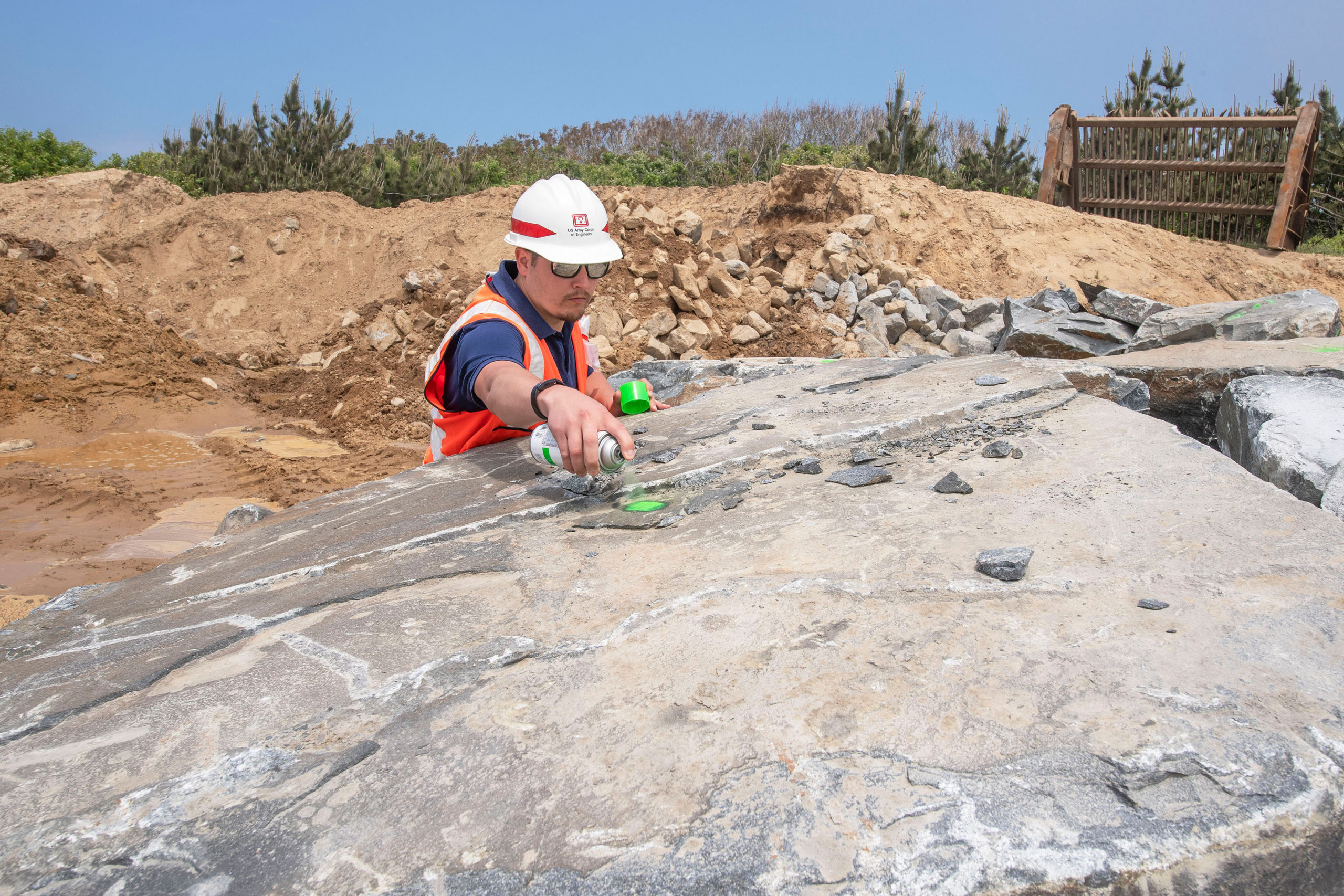 U.S. Army Corps of Engineers Quality Assurance Officer Mike Folcik spray paints a mark on a large boulder to signify that it has passed his inspection (no cracks, etc.) as part of the Army Corps of Engineers' Montauk Point Revetment Project on Monday.  MICHAEL HELLER