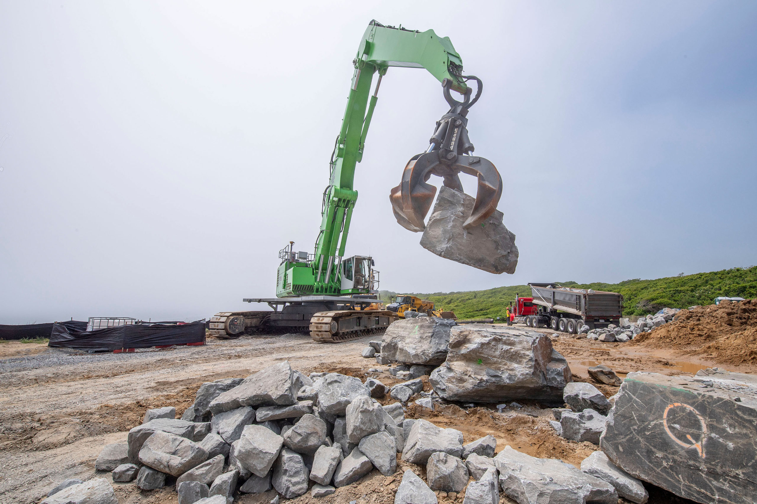 Large boulders - some as large as 15 tons - are moved by a large claw-tipped excavator after being transported from a quarry in upstate New York as part of the Army Corps of Engineers' Montauk Point Revetment Project on Monday.  MICHAEL HELLER