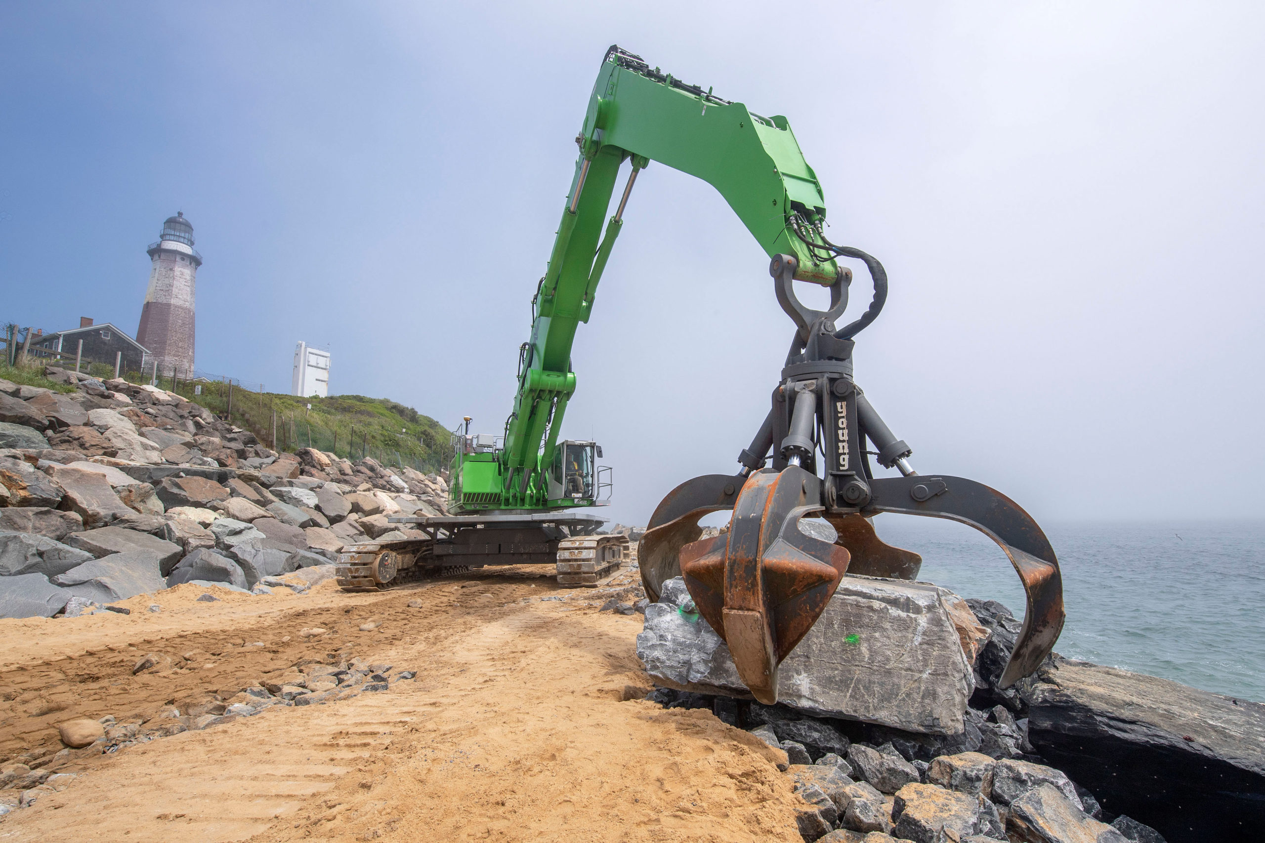 Large boulders - some as large as 15 tons - are moved by a large claw-tipped excavator after being transported from a quarry in upstate New York as part of the Army Corps of Engineers' Montauk Point Revetment Project on Monday.   MICHAEL HELLER