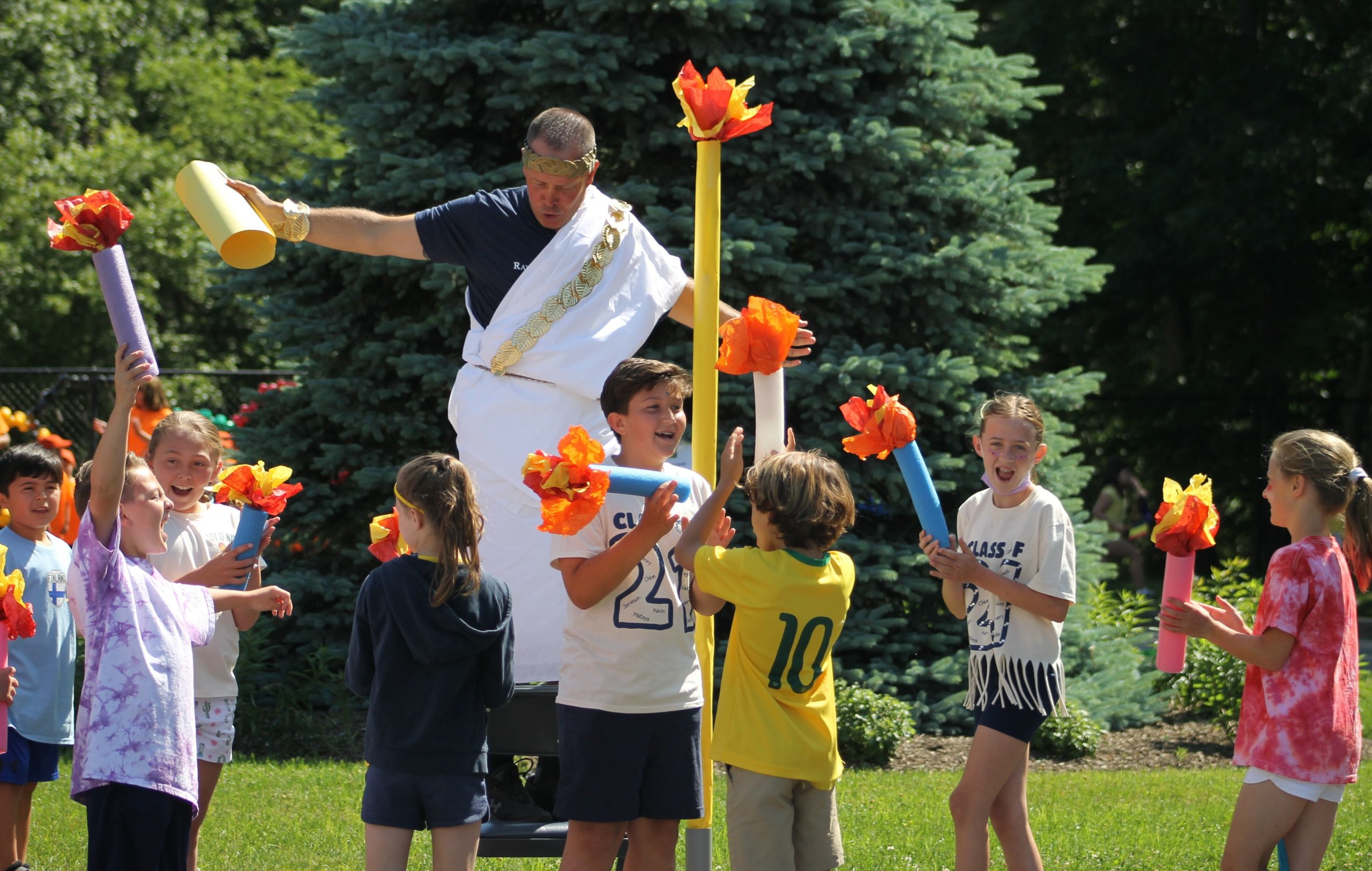 PE Coach, Erik Broskie, celebrates with students once the torch is lit during Raynor Country Day School's Olympic Field Day event.