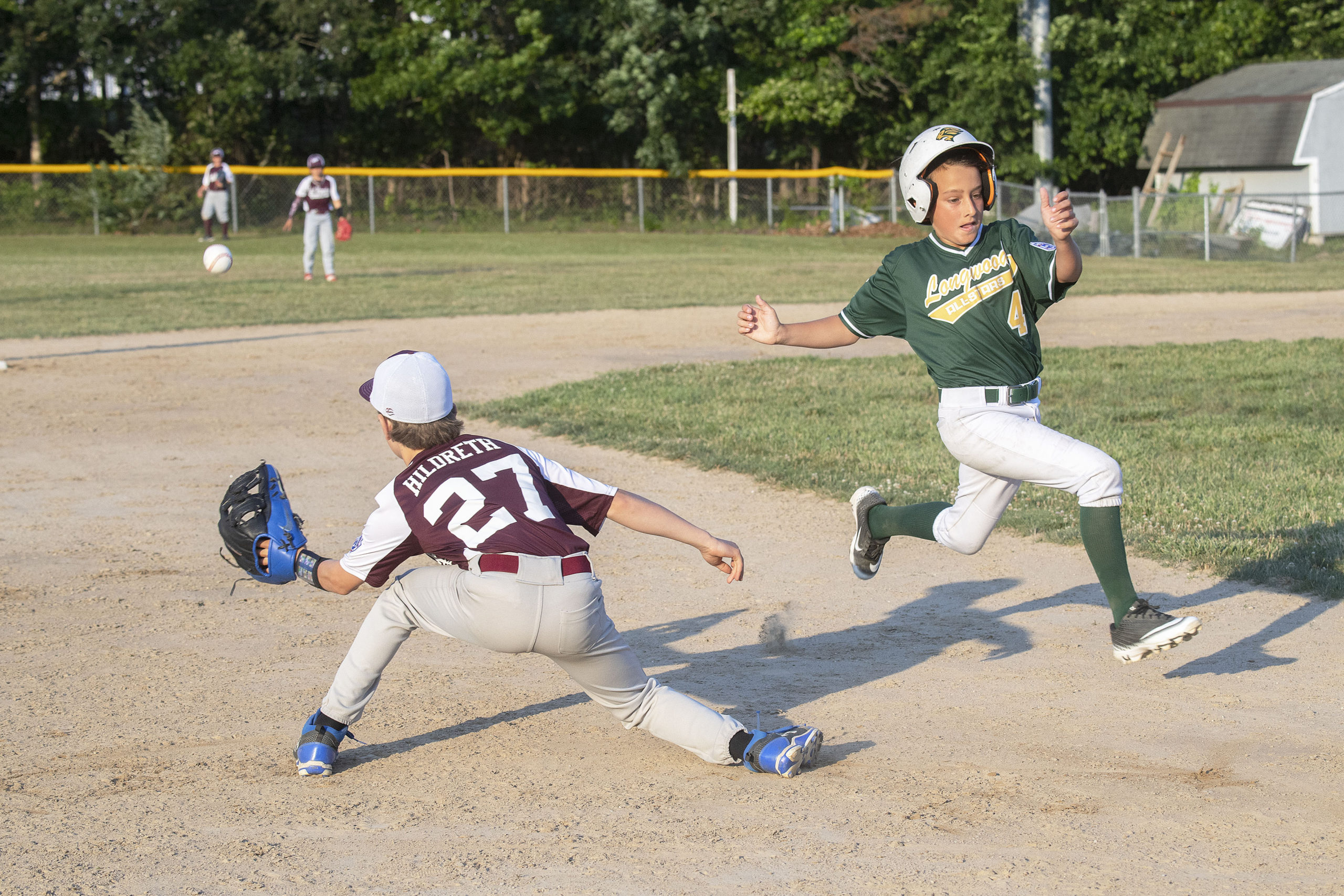 A throw from the outfield comes in too late for East Hampton's Kieran Hildreth at third base.