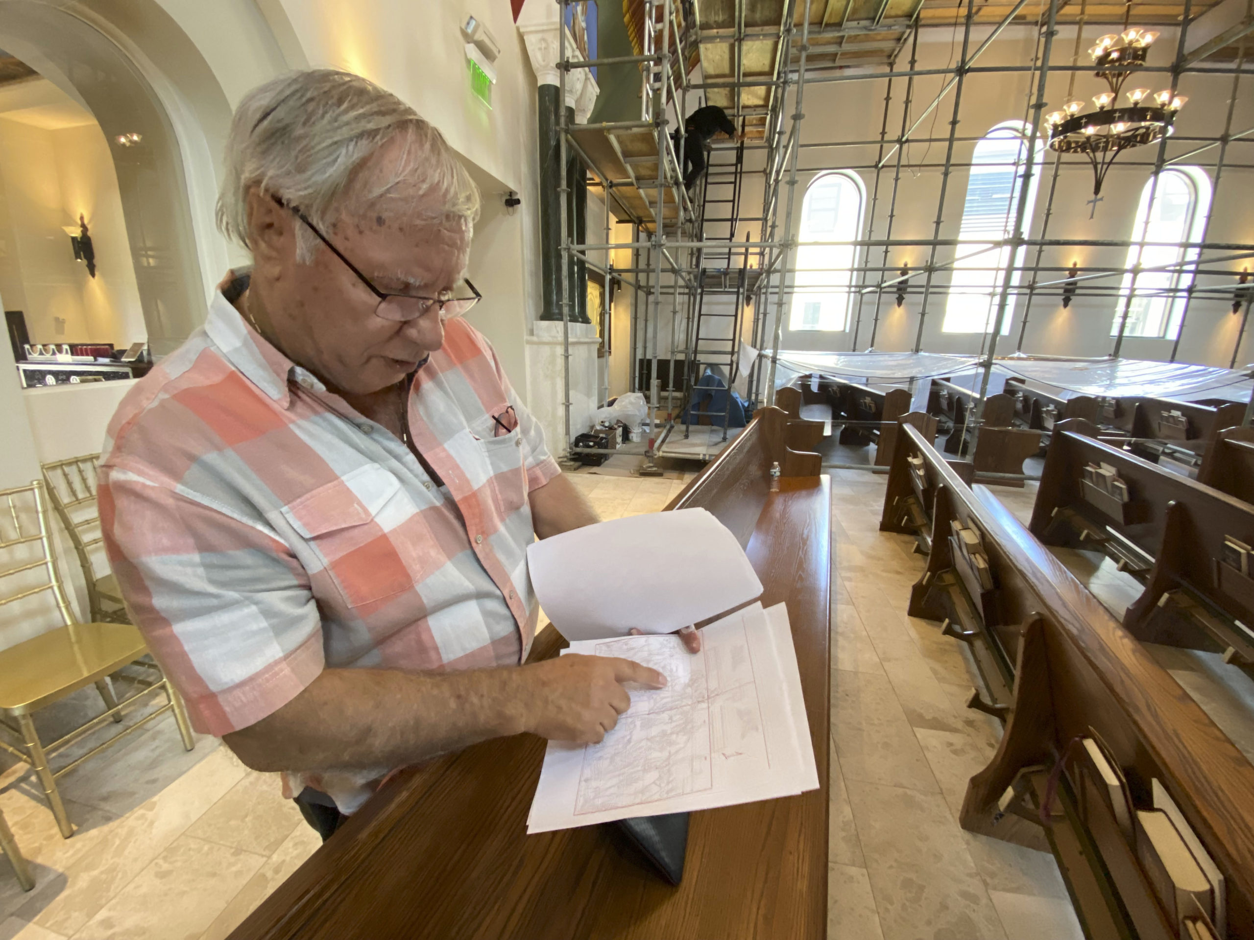 Iconographer George Filippakis  with sketches of the remaining works on the ceiling of the Dormition of the Virgin Mary Greek Orthodox Church. The church will be his last work.  DANA SHAW