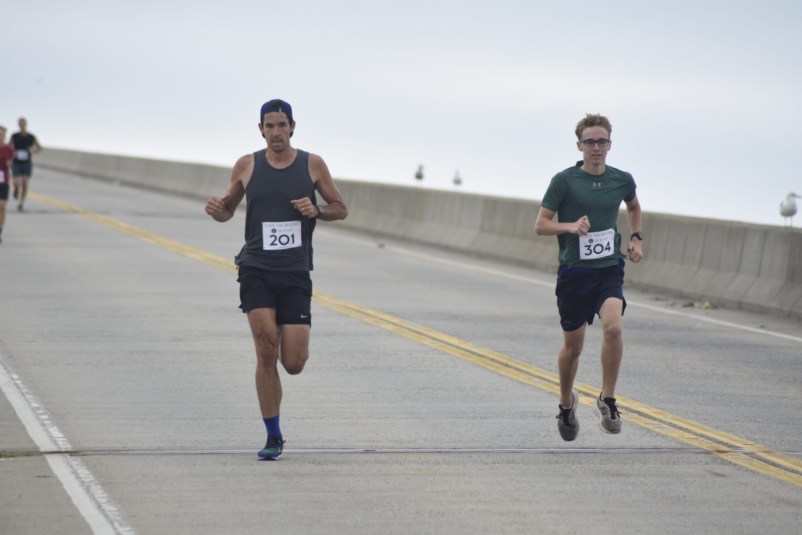 Jack Stevens, left, and Luca Villano lead the initial pack of runners over Ponquogue Bridge on Saturday morning. Stevens and Villano finished first and second, respectively, in the 5K.