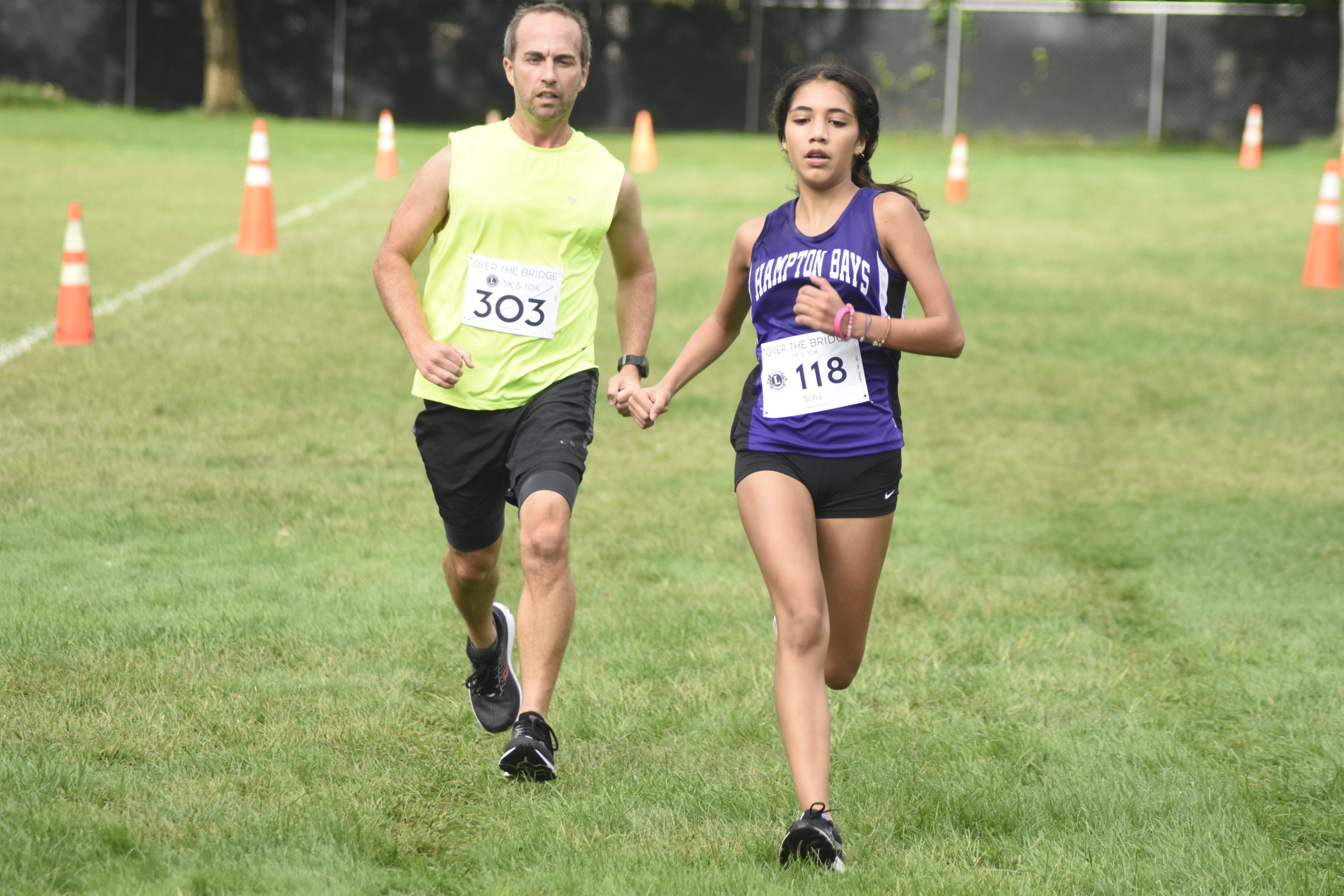 Hampton Bays girls cross country head coach Kevin O'Toole crosses the finish line with one of his runners Sofia Galavan.