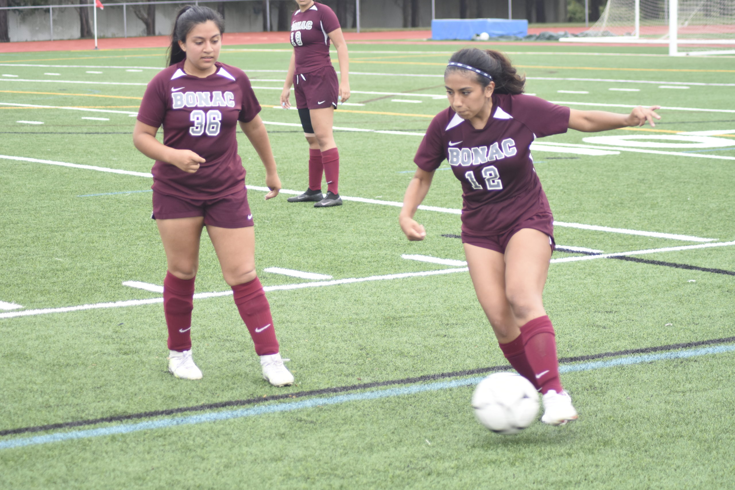 With junior Tiffany Pesantez looking on, junior Bonacker Nicole Velez plays the ball near the sideline.