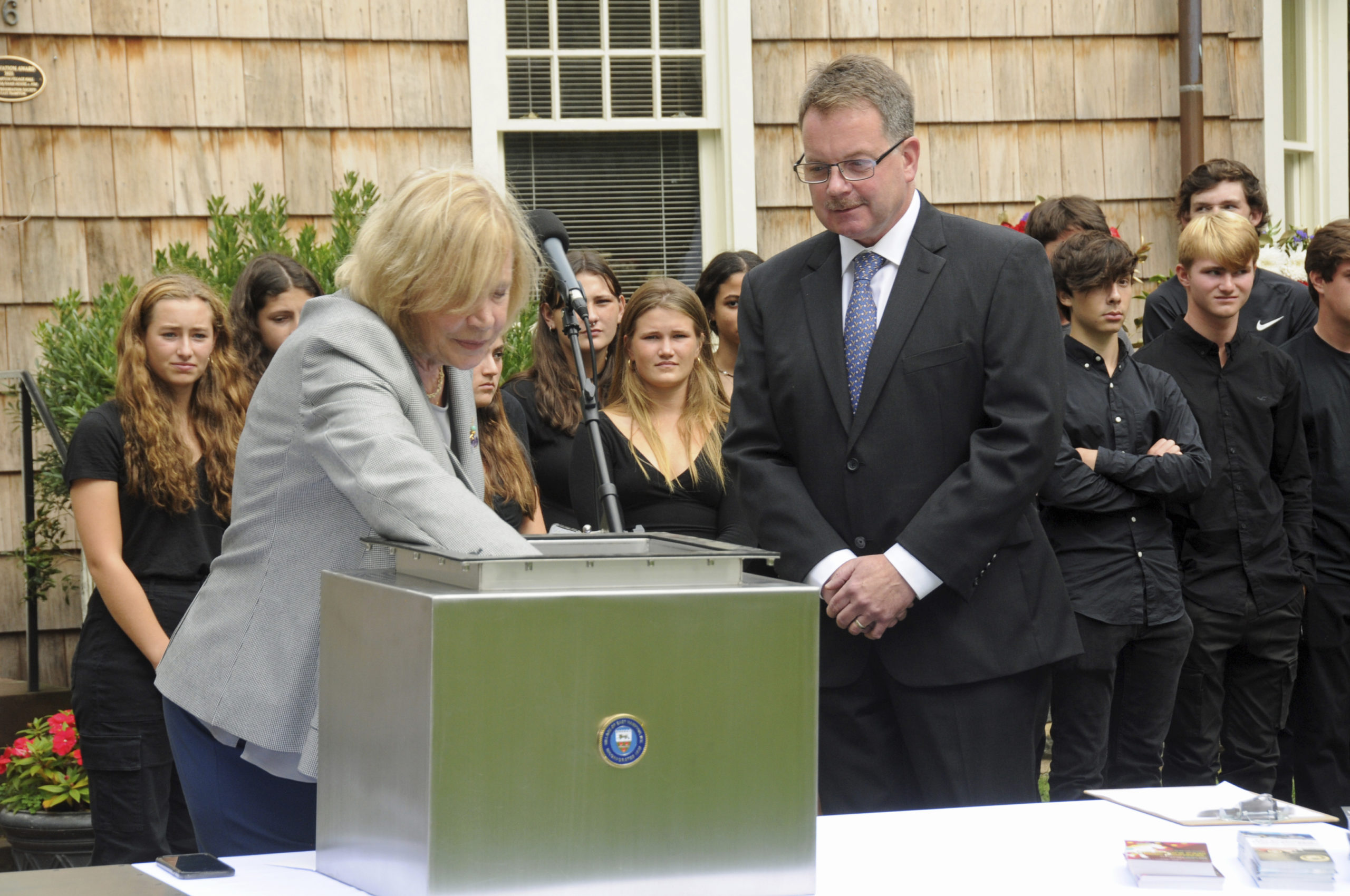 Ladies village Improvement Society President Jennifer Tarbet places an item in the time capsule as Mayor Jerry Larsen looks on.