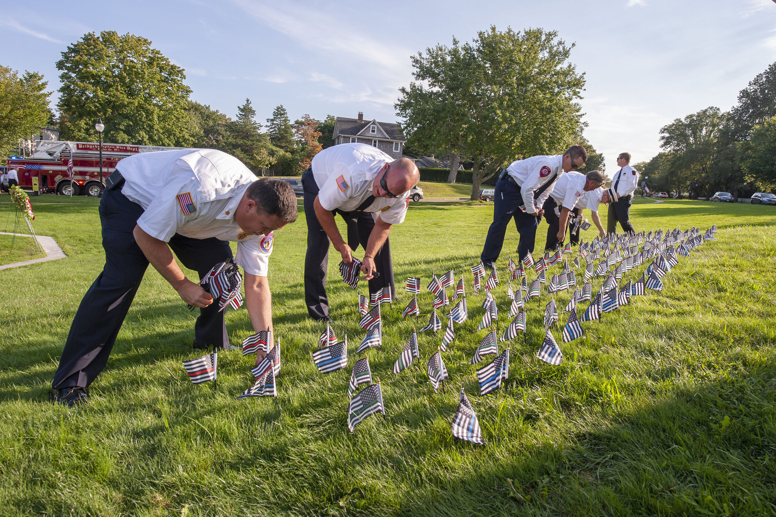 Firefighters from the Amagansett, Springs and Sag Harbor Fire Departments plant flags - one for each fire, police or military member killed at 9/11 - prior to the start of the ceremony commemorating the 20th anniversary of the attack on the World Trade Center, held on the Village Green in East Hampton on Saturday afternoon.
