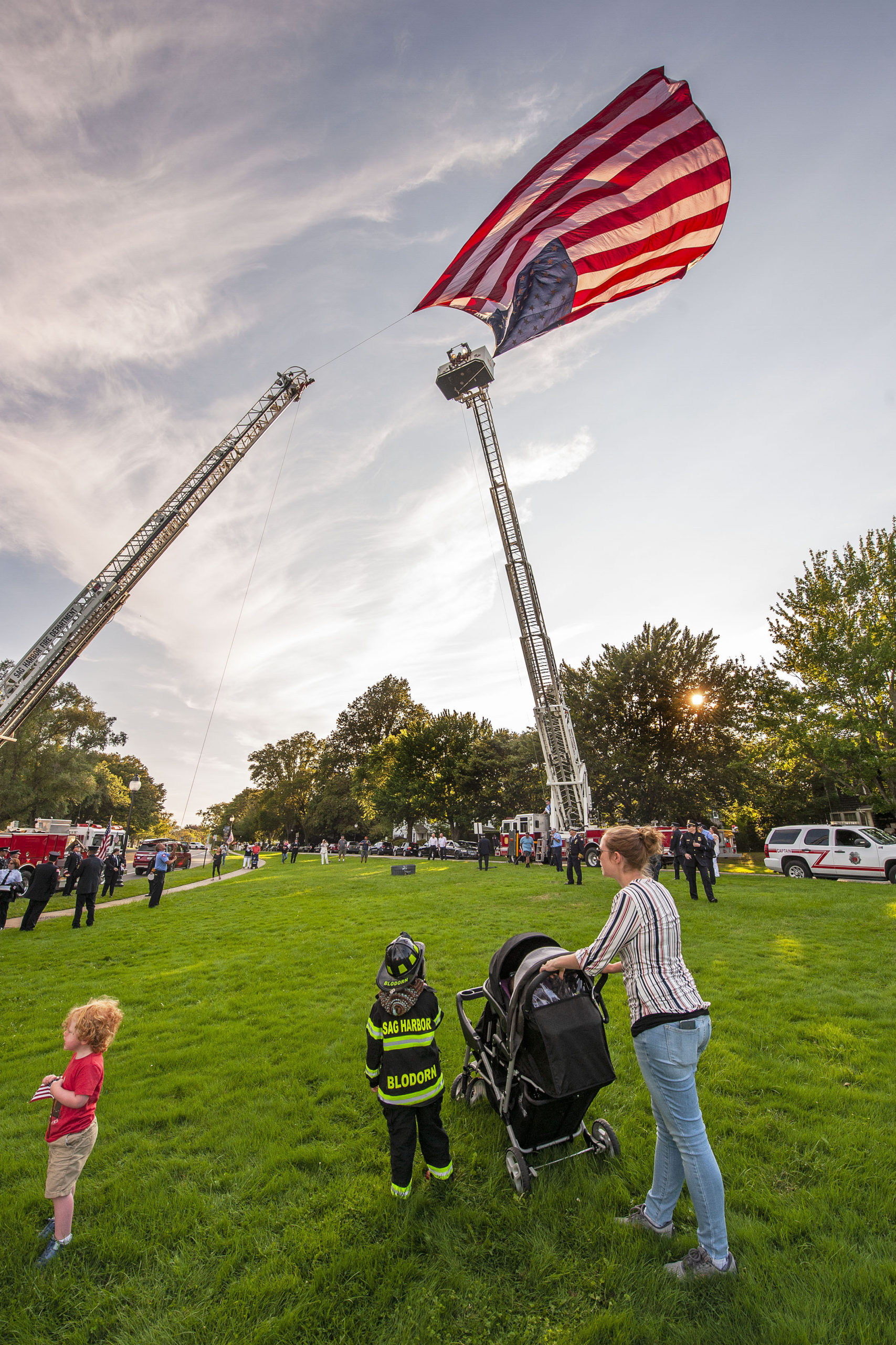 Five-year-old Connor Blodorn, son of Sag Harbor Fire Department Assistant Chief Andrew Blodorn, watches the American flag being raised by the East Hampton and Sag Harbor Fire Department ladder trucks prior to the start of the ceremony commemorating the 20th anniversary of the attack on the World Trade Center, held on the Village Green in East Hampton on Saturday afternoon.