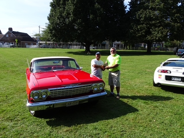 Todd Tureski presents the People's Choice trophy to Tom Federico, owner of the 1962 Chevy Impala SS, at the Water Mill Classic Car Show on Saturday.