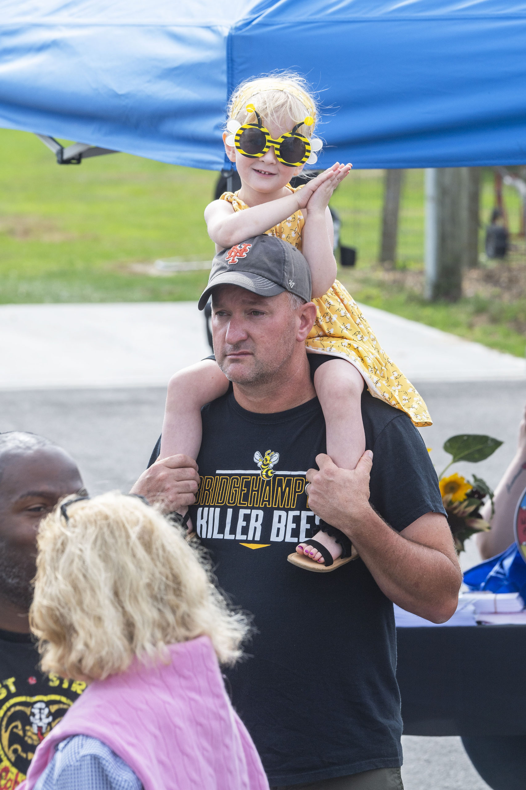Four-year-old Georgia Kaiser watches the ribbon-cutting ceremony from dad Cameron's shoulders during the first annual Bridgehampton Community Day that was held behind the Bridgehampton School on Saturday.    MICHAEL HELLER