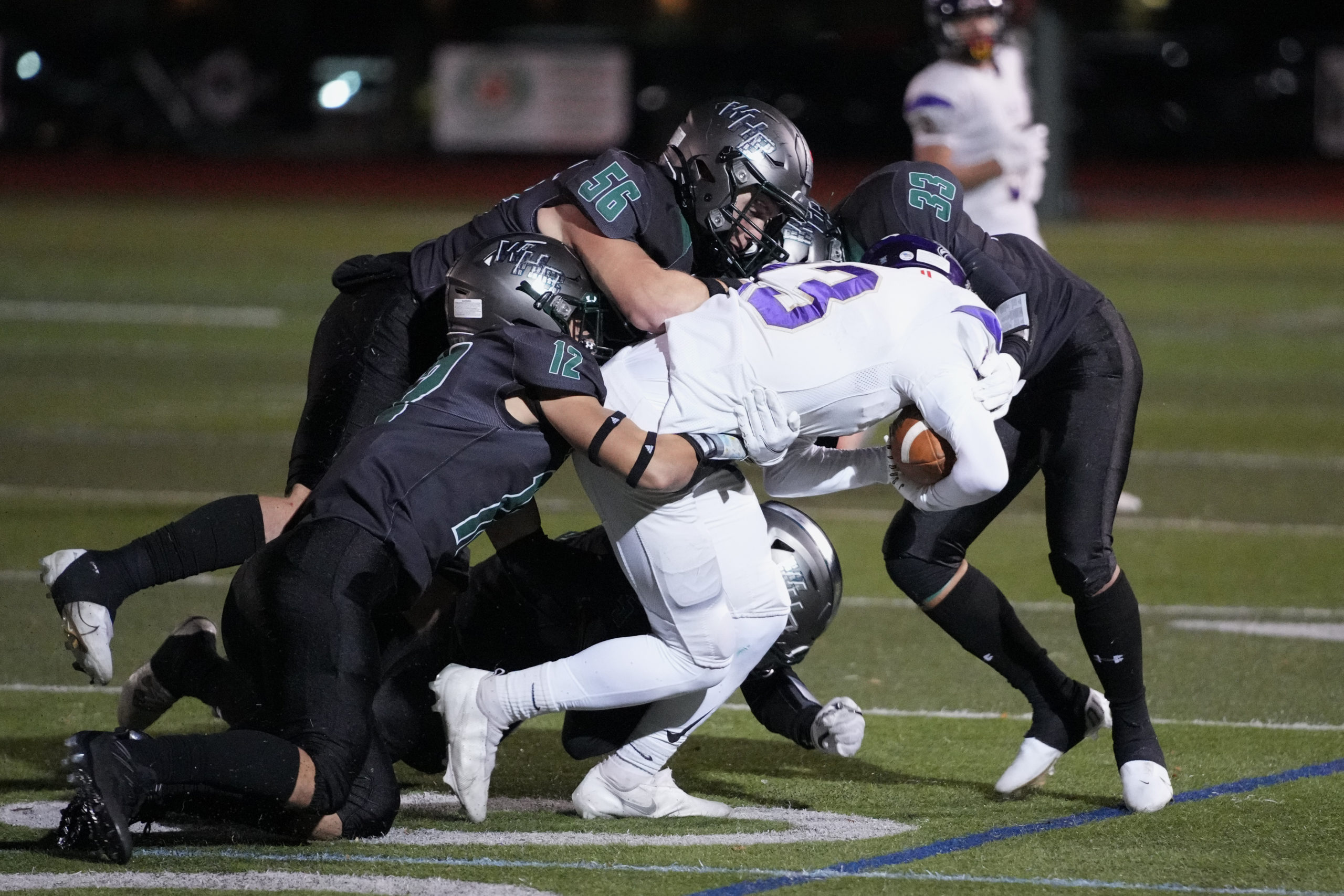 Hurricanes Deegan Laube (12), Frank Noto (56) and Ethan Faralan team up for a tackle.