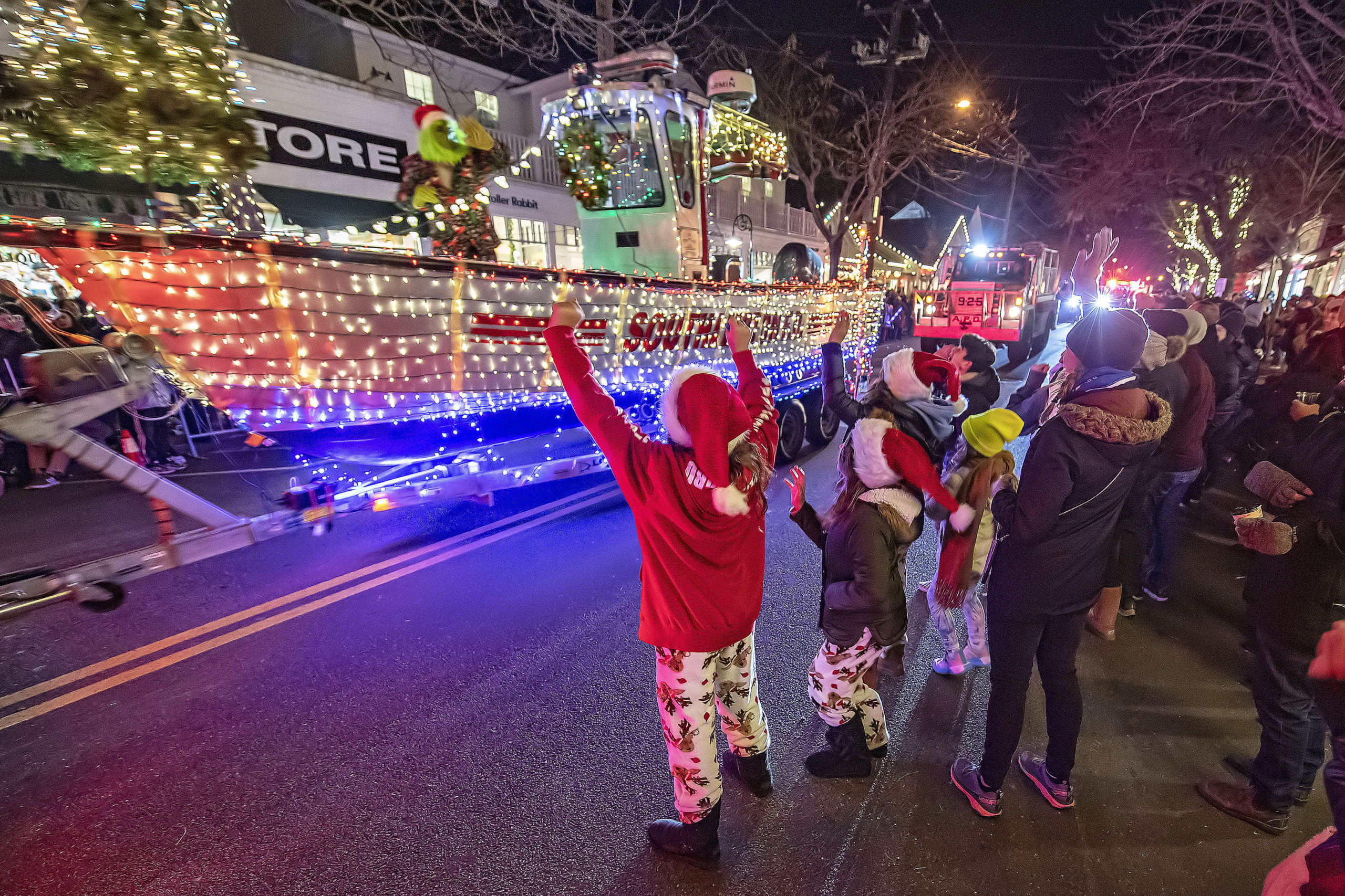 Kids welcome the Grinch as he rides on the Southampton Fire Department rescue boat  during the 2021 Parade of Lights along Jobs Lane on Saturday night.   MICHAEL HELLER