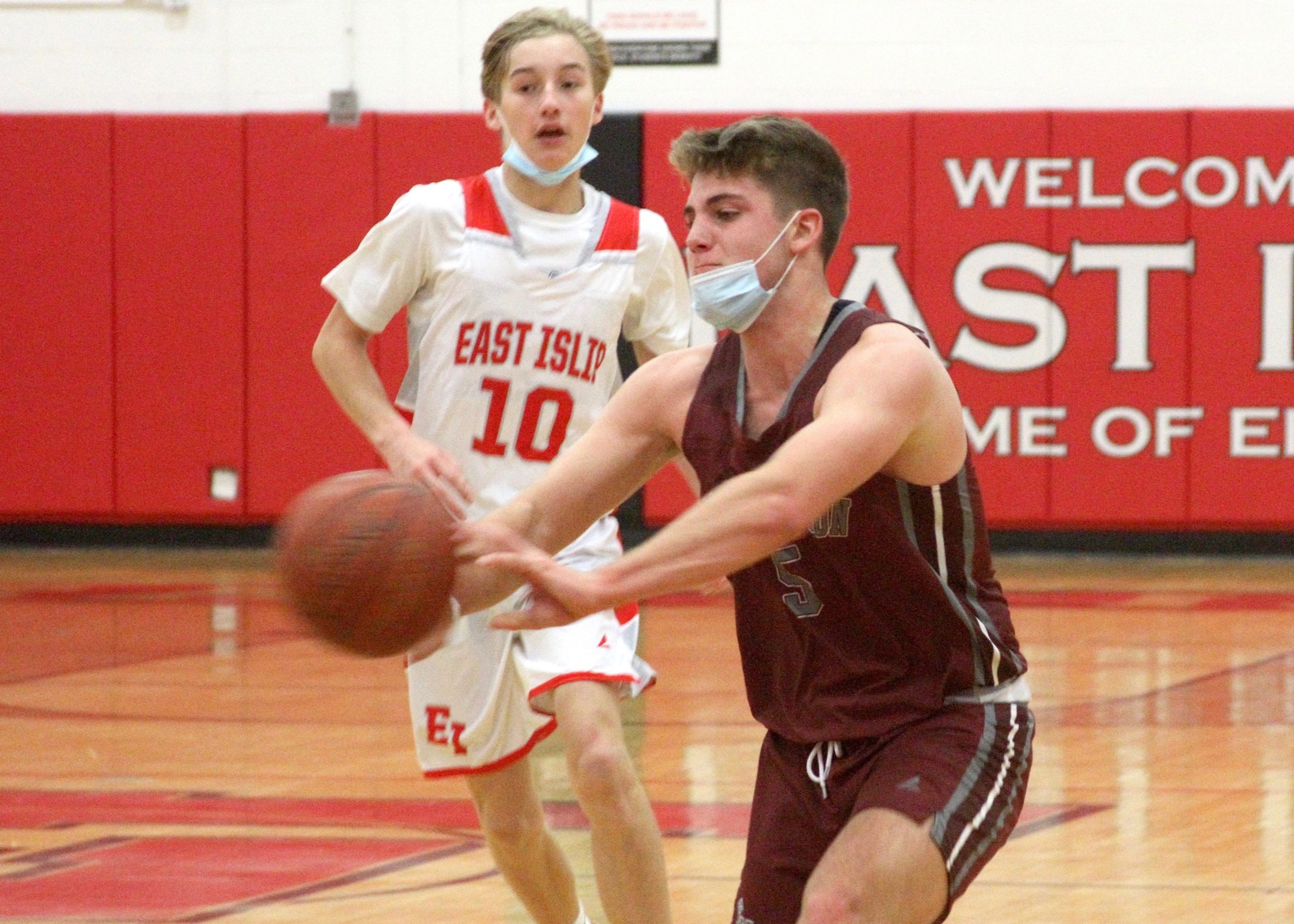 Junior guard Jack Dickinson passes the ball under the basket with East Islip's John Talt racing from behind. DESIRÉE KEEGAN