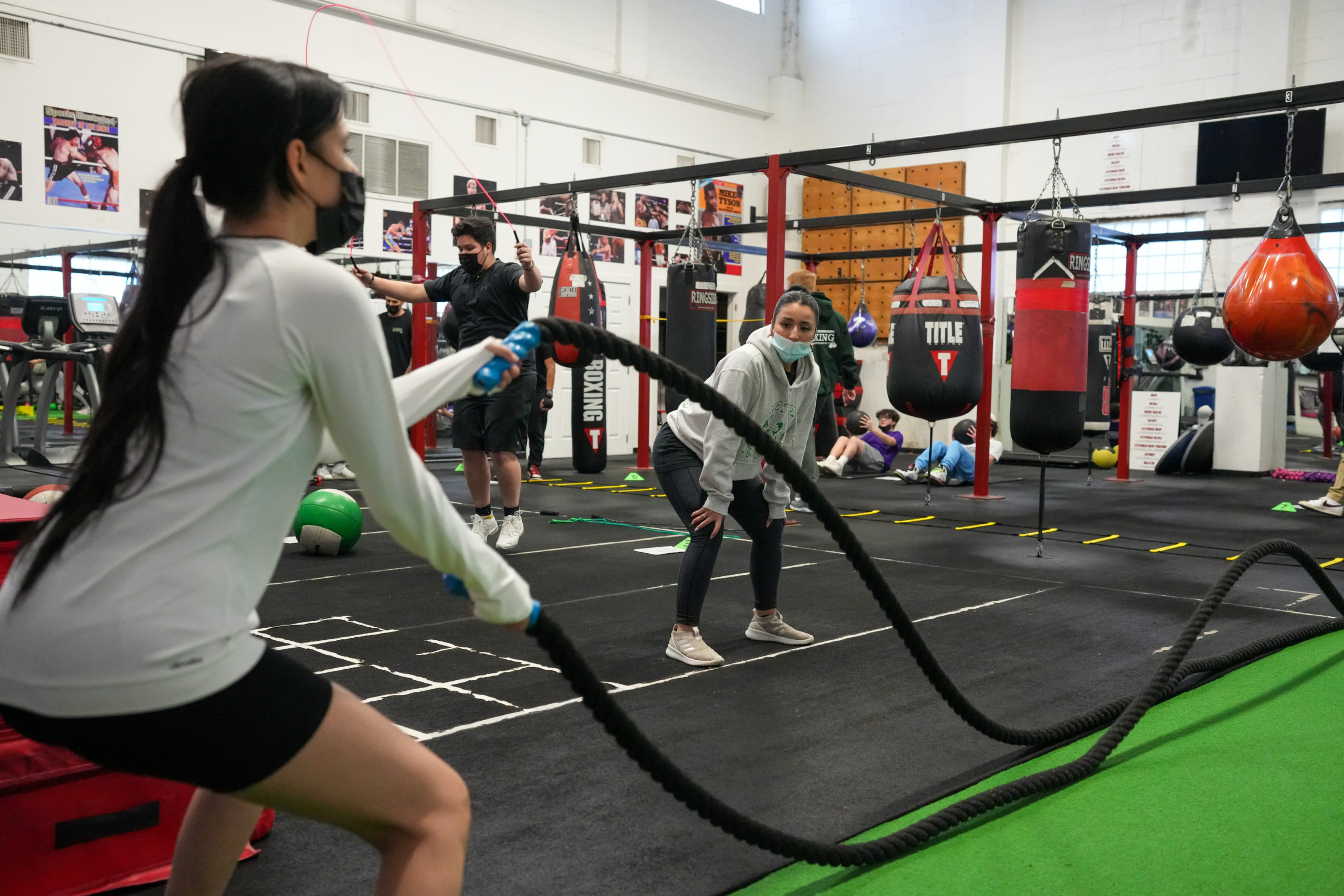 Hampton Bays ENL teacher Daniela Vargas, on right, watches student Marianna Iriarte Ospina as she works with battle ropes. RON ESPOSITO