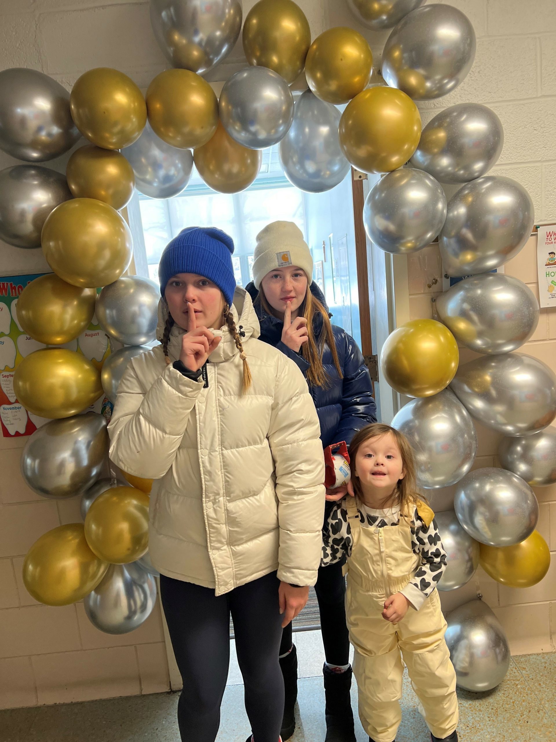 Our Lady of the Hamptons School studnts Ava, Estee and Macie Phair preparing for a special surprise to honor school nurse Eileen Shimkus.