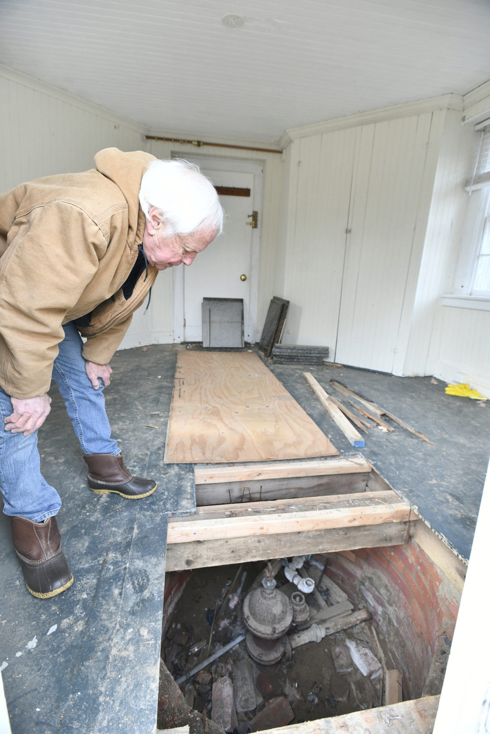 Larry Jones examines the original water well and pump.  DANA SHAW