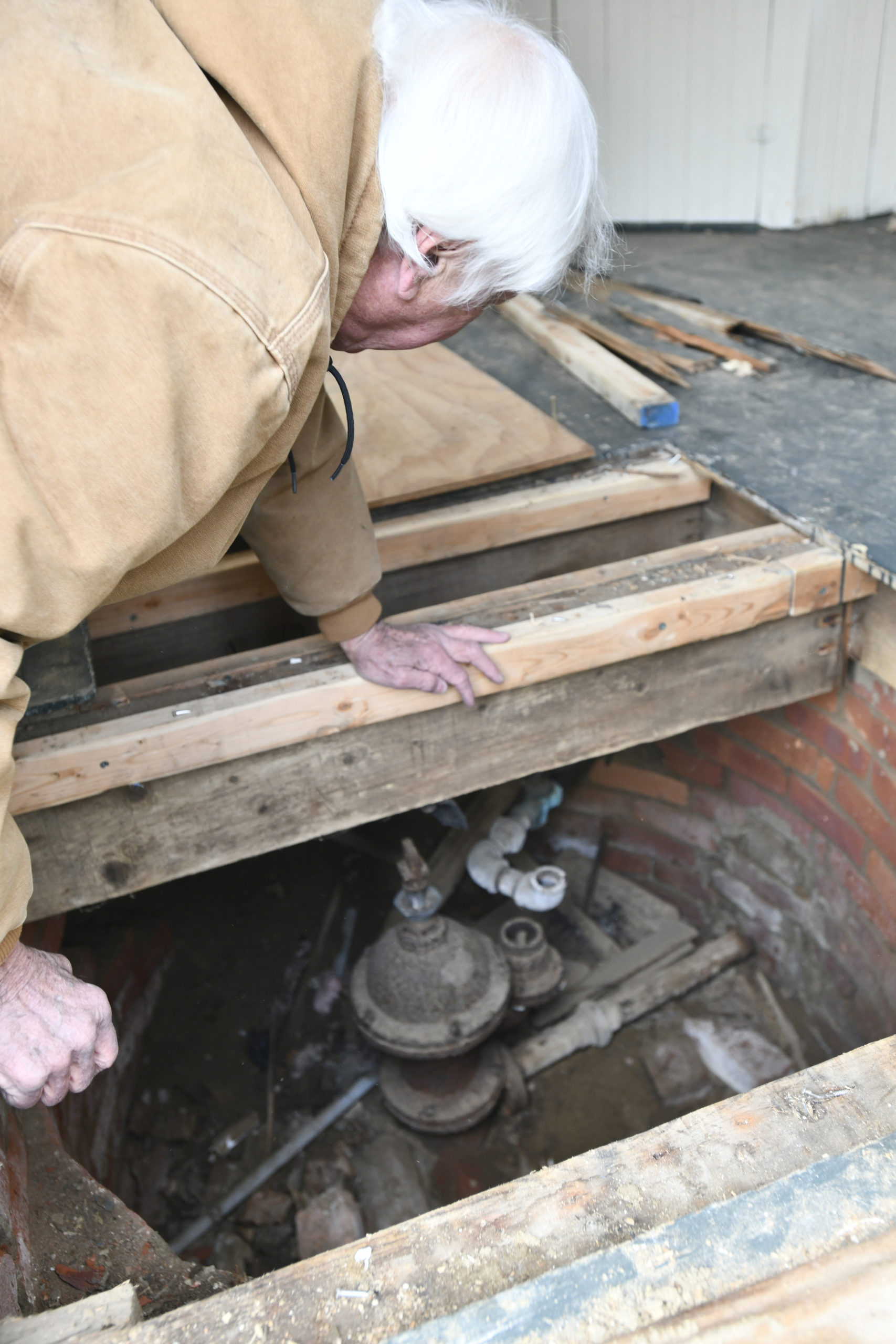 Larry Jones examines the original water well and pump.  DANA SHAW