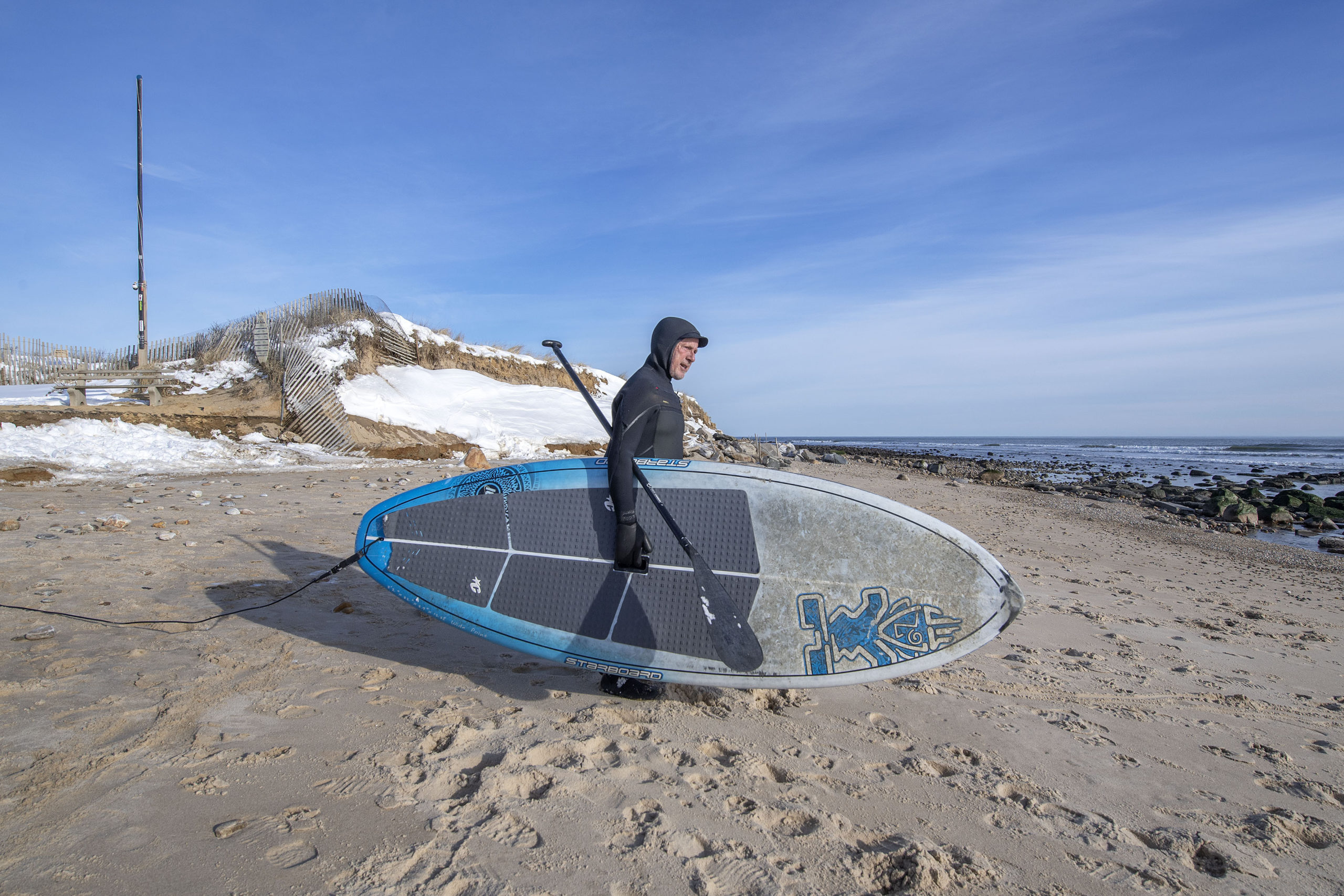 A wetsuit-clad paddleboarder takes to the water at Ditch Plains Beach in Montauk on a frigid January day on Monday.  MICHAEL HELLER