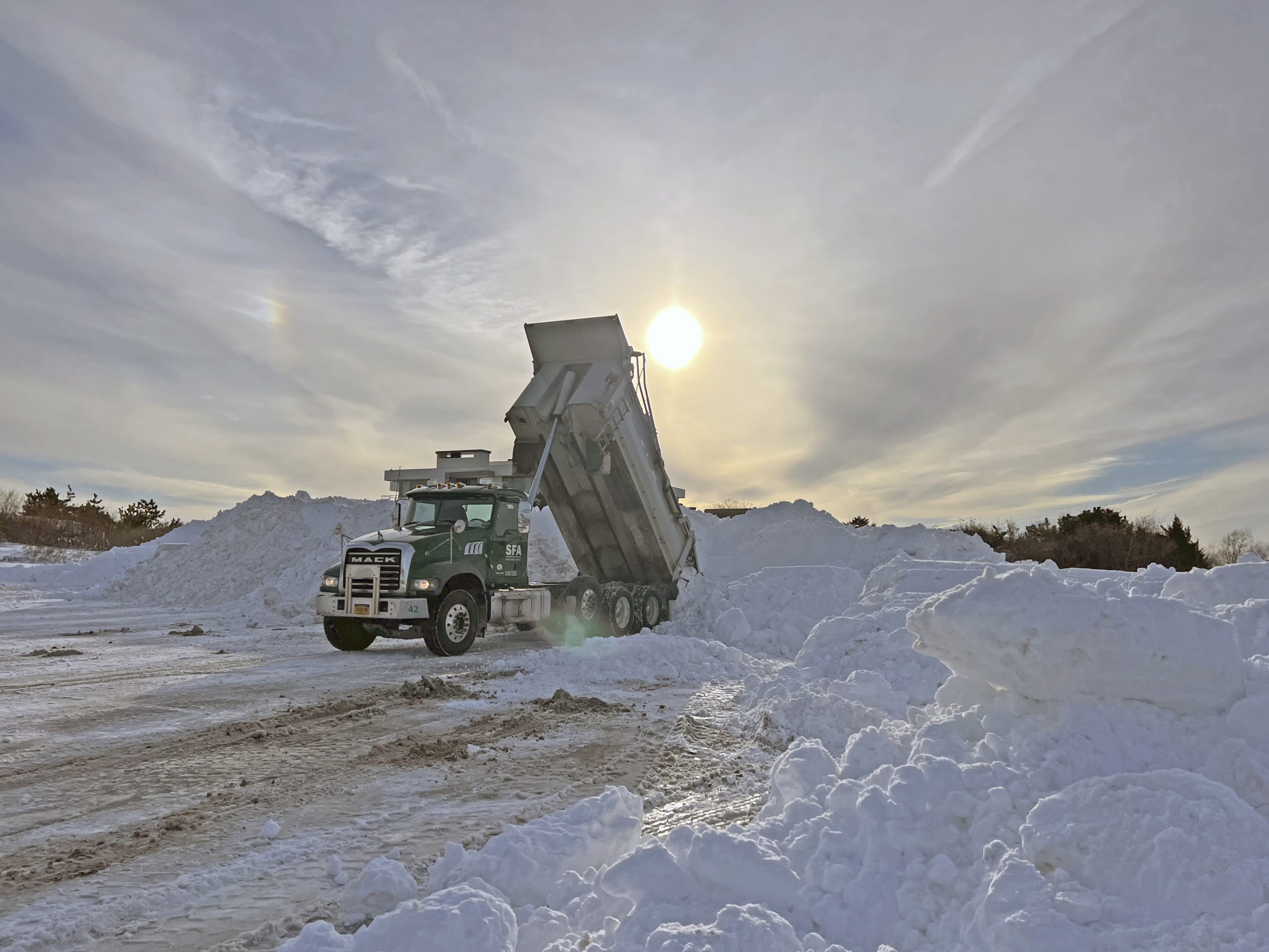 A steady stream of dump trucks deposit tons of snow taken from area streets in the parking lot of Coopers Beach in Southampton Village on Monday afternoon.  Municipalities, businesses and residents are still digging out after a massive snow storm blew through the area this weekend.  DANA SHAW