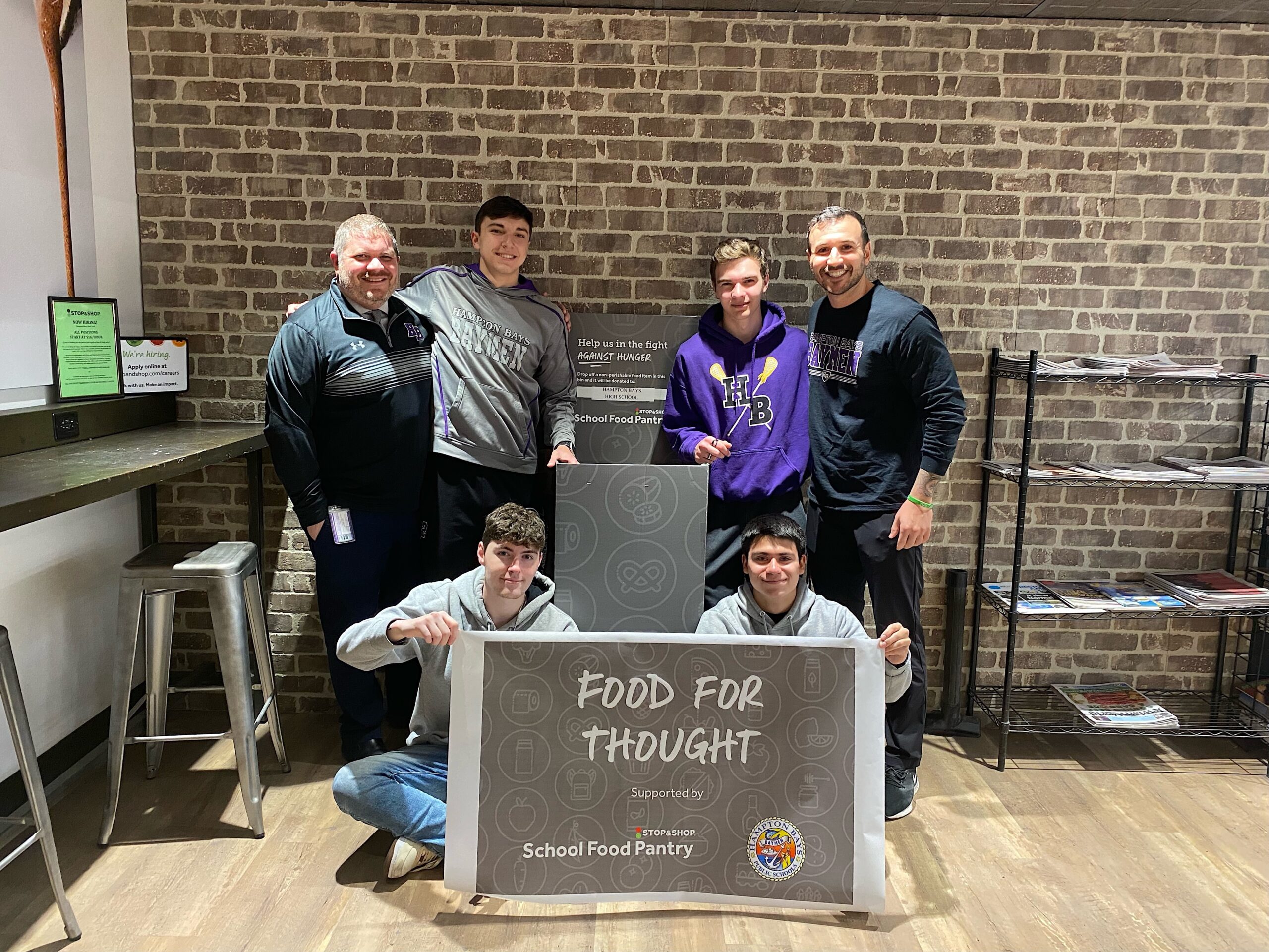 Hampton Bays Executive Director for Educational Services & School Safety, Eric Ferraro, seniors James Kiernan and Ben Madison, social worker Chris DeRosa and seniors Dillon Ottati and Chris Sanchez unveil the Food For Thought donation bin at Stop & Shop, which will help stock the shelves of the new high school food pantry. HAMPTON BAYS SCHOOL DISTRICT