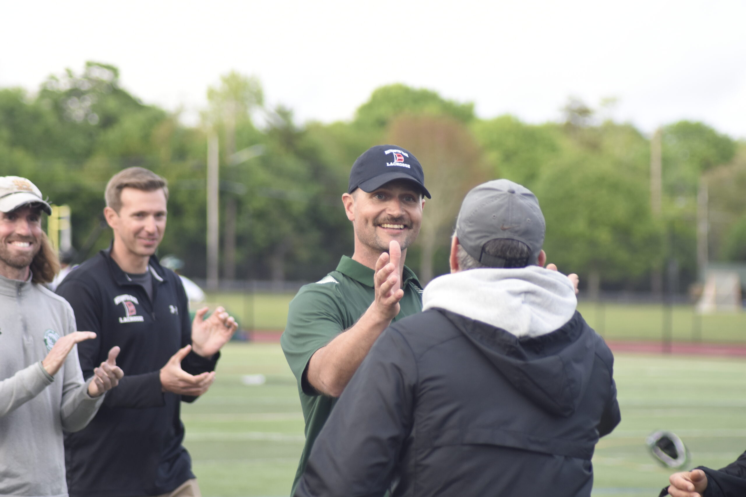 Westhampton Beach head coach Drew Peters, assistant coach Ralph Naglieri and the rest of the coaching staff congratulate one another on their first playoff win.   DREW BUDD