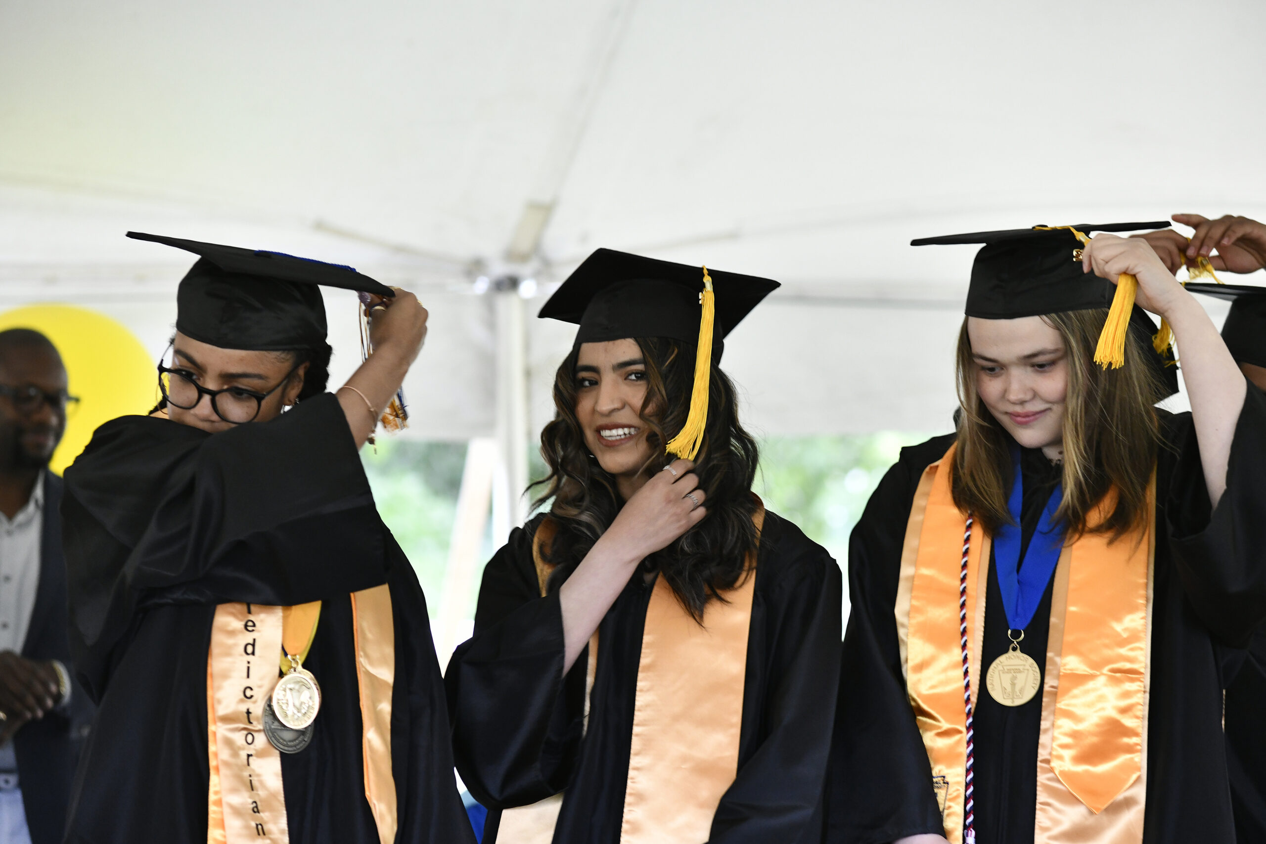 Ayanna El, Perla Cruz and Uma Comfort move their tassels after graduation.