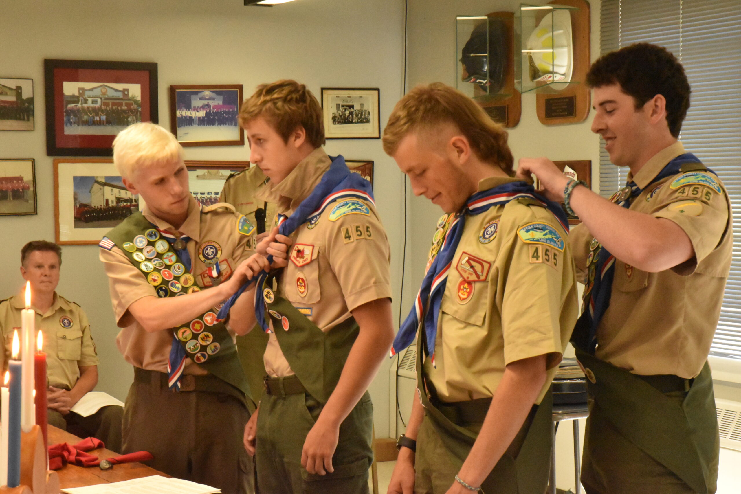 Eagle Scout Tristan Remkus, left, assists his younger brother, Troy Remkus, with his Eagle Scout neckerchief, while Eagle Scout Ryan Brown, right, assists James Farrell at  Sunday's Court of Honor in Sag Harbor. STEPHEN J. KOTZ