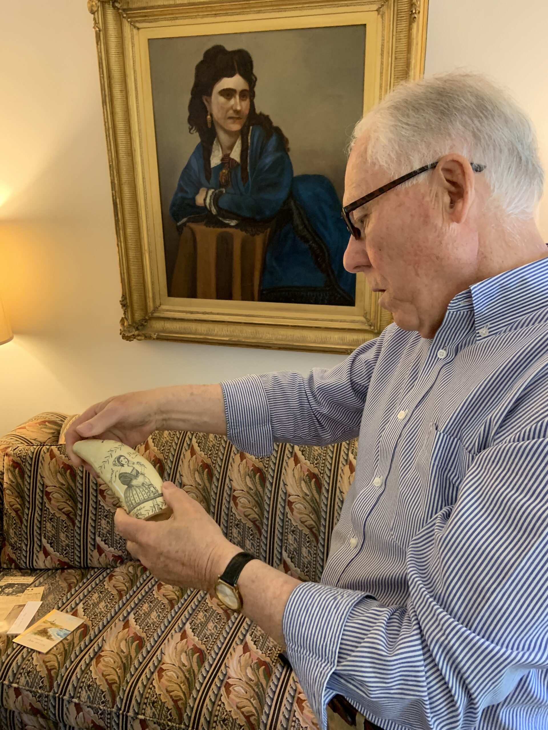 Jack Youngs examines a replica piece of scrimshaw at his home on Harbor Watch Court. STEPHEN J. KOTZ