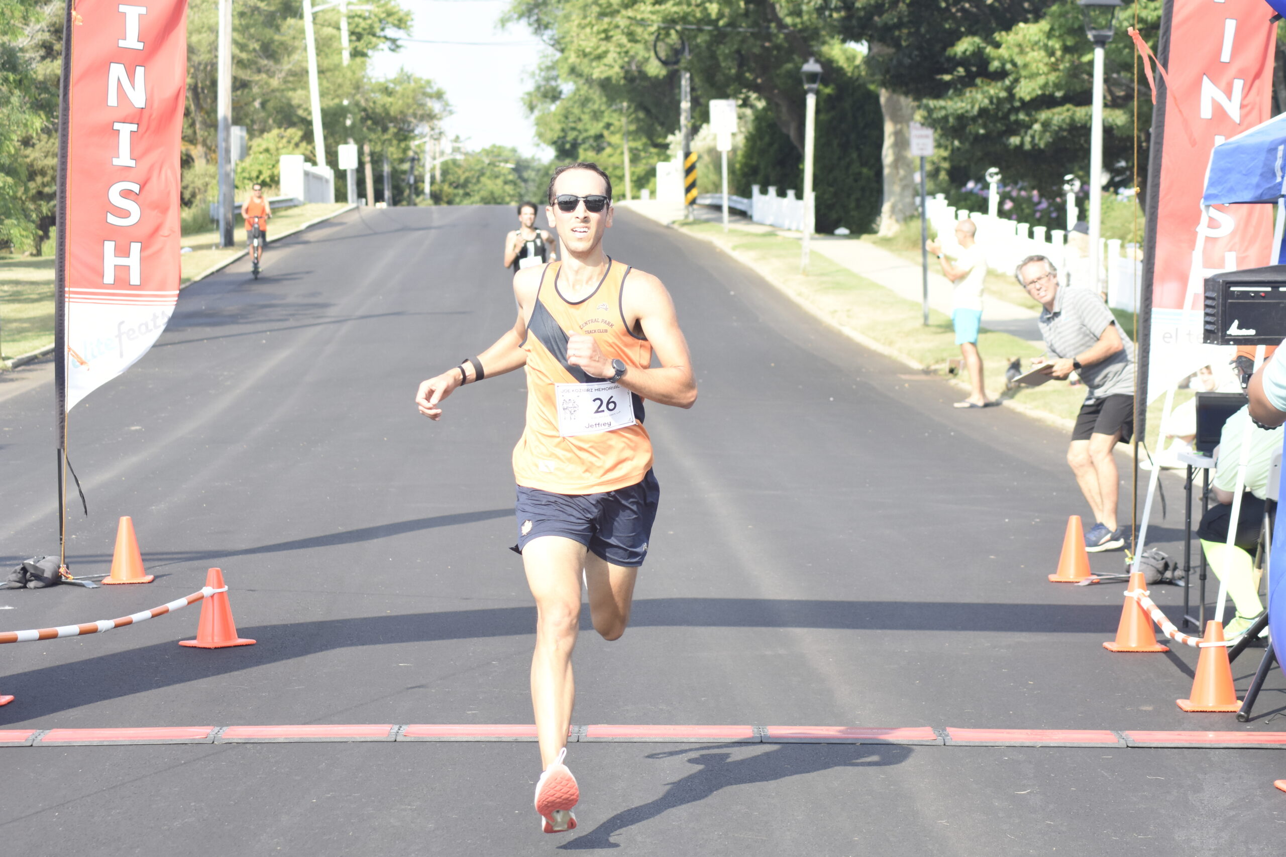 Jeffrey Ares of New York City and Westhampton Beach is the first to cross the finish line in the Joe Koziarz Memorial 5K.    DREW BUDD