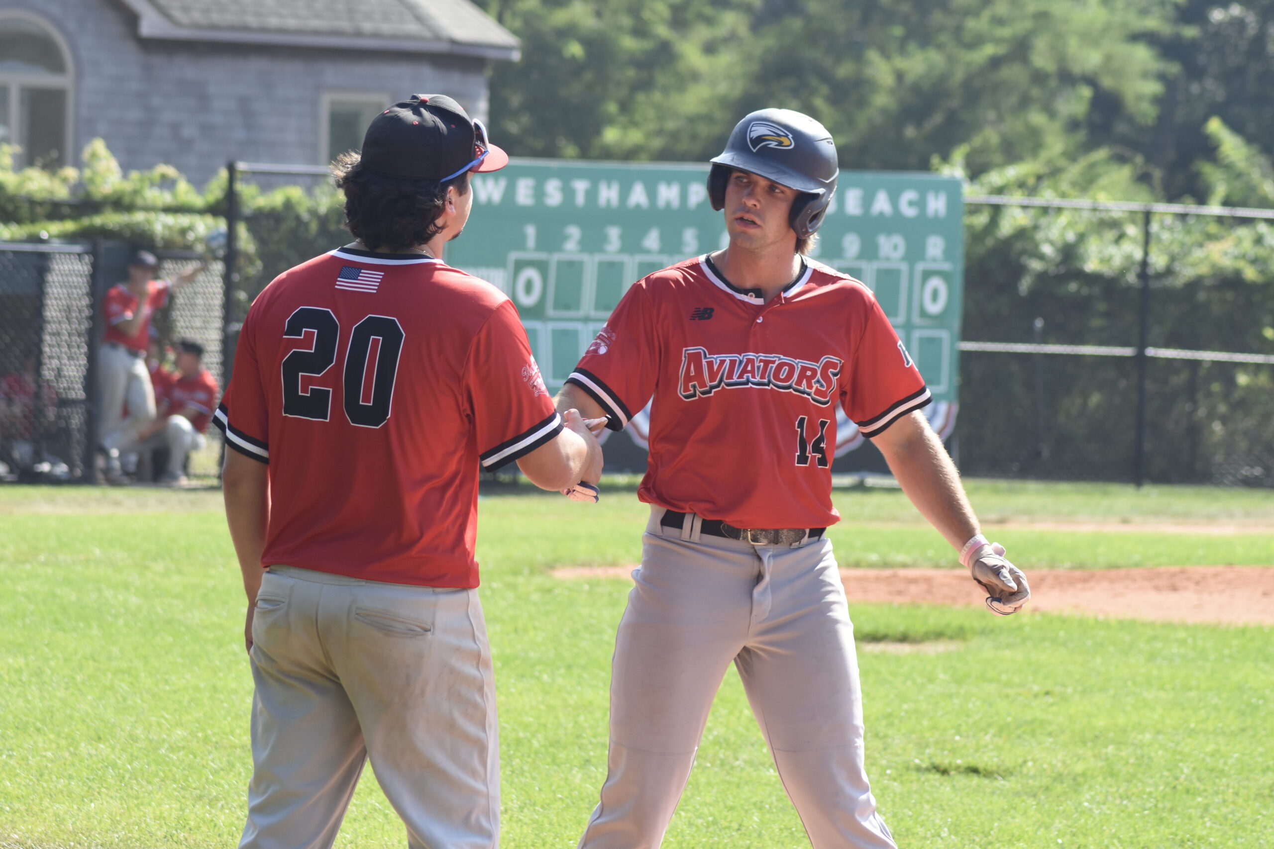 Jack Halloran (Emory) is congratulated by first base coach and teammate Michael DiForte after a base hit.   DREW BUDD