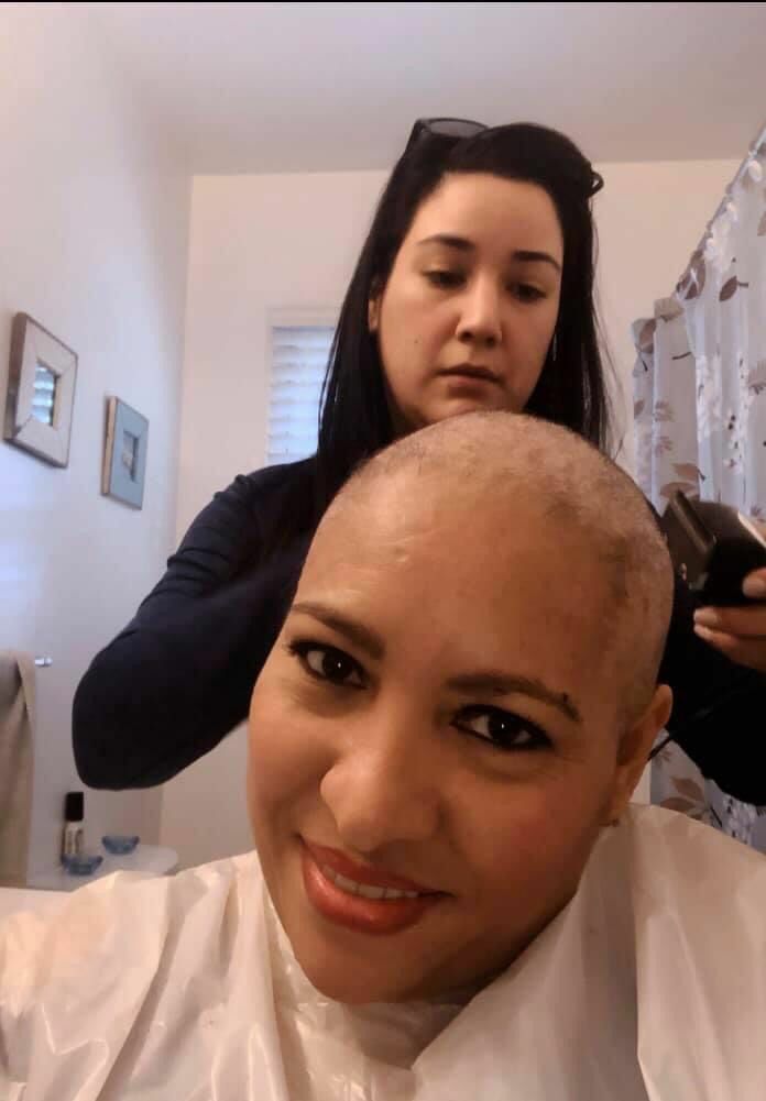 Alma Tovar, OLA's outreach coordinator and transportation advocate, helps a client and cancer survivor with a haircut. COURTESY MINERVA PEREZ