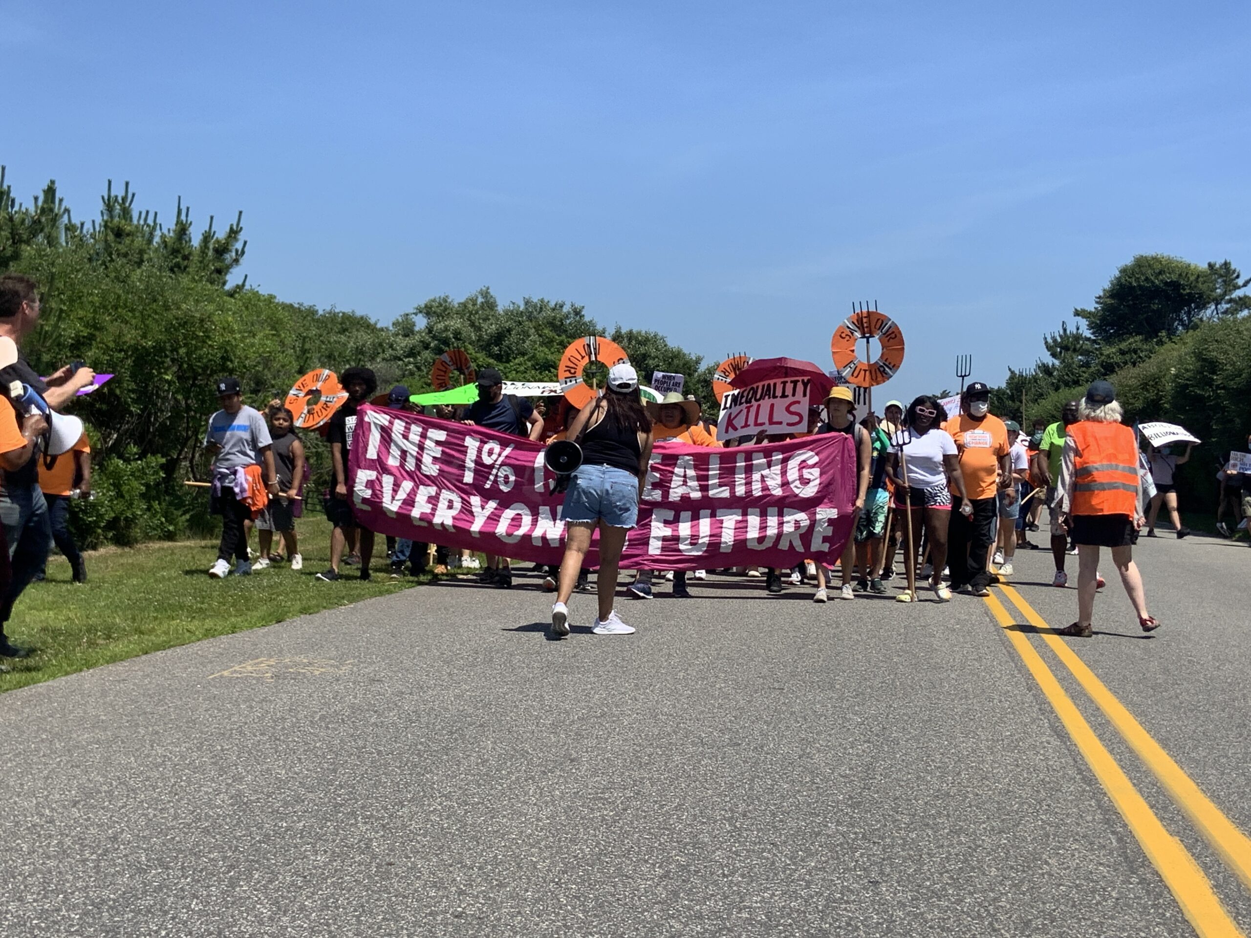 Protesters calling for higher taxes on billionaires to help cover the costs of everything from childcare to climate change mitigation, marched on Meadow Lane in Southampton Village on Saturday.  STEPHEN J. KOTZ
