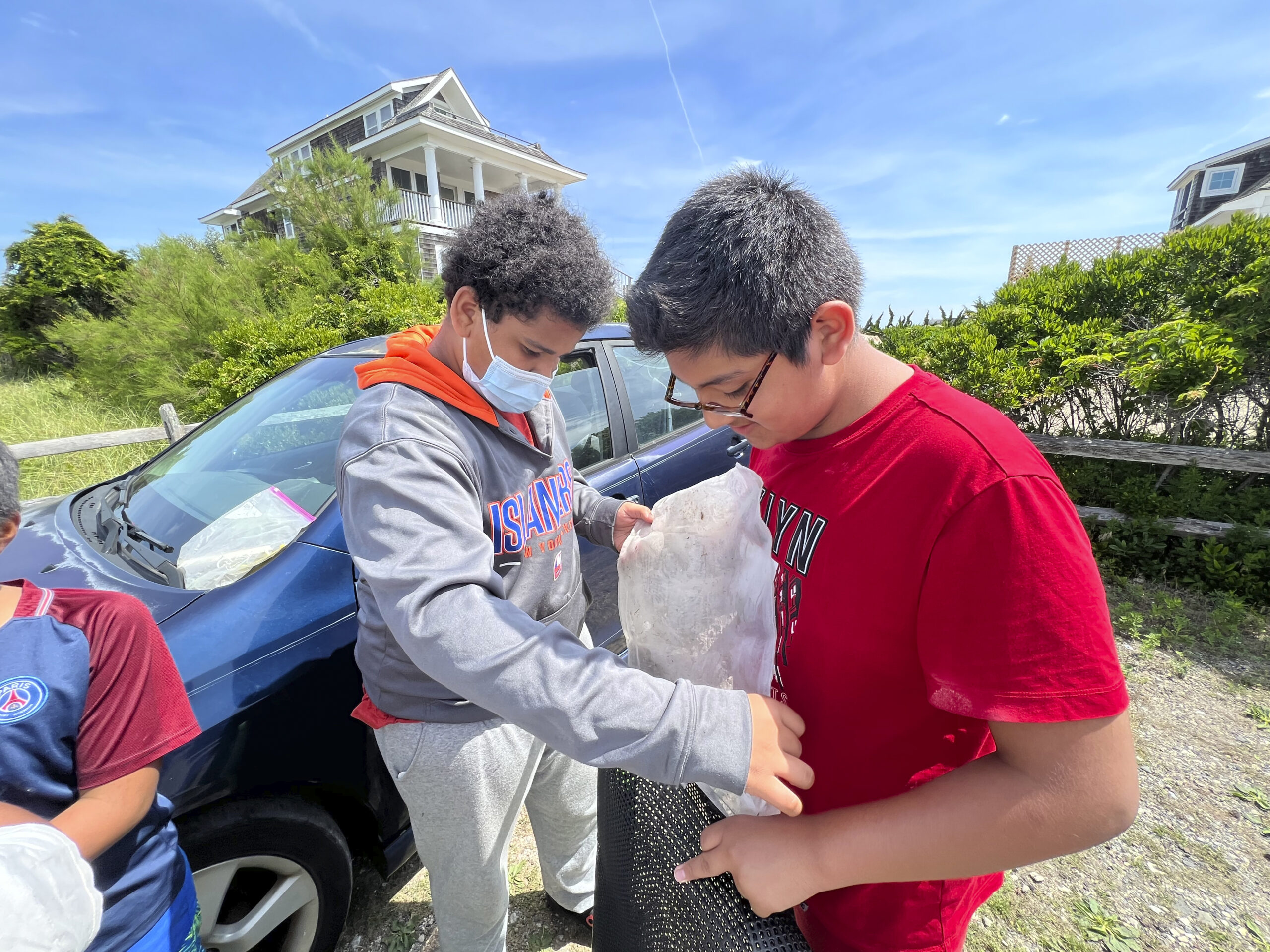 Kids from the Bridgehampton Child Care and Recreational Center add oyster to their cages at the Moriches Bay Project's learn how to make and oyster cage and set up a farm event in Westhampton on July 8.    DANA SHAW
