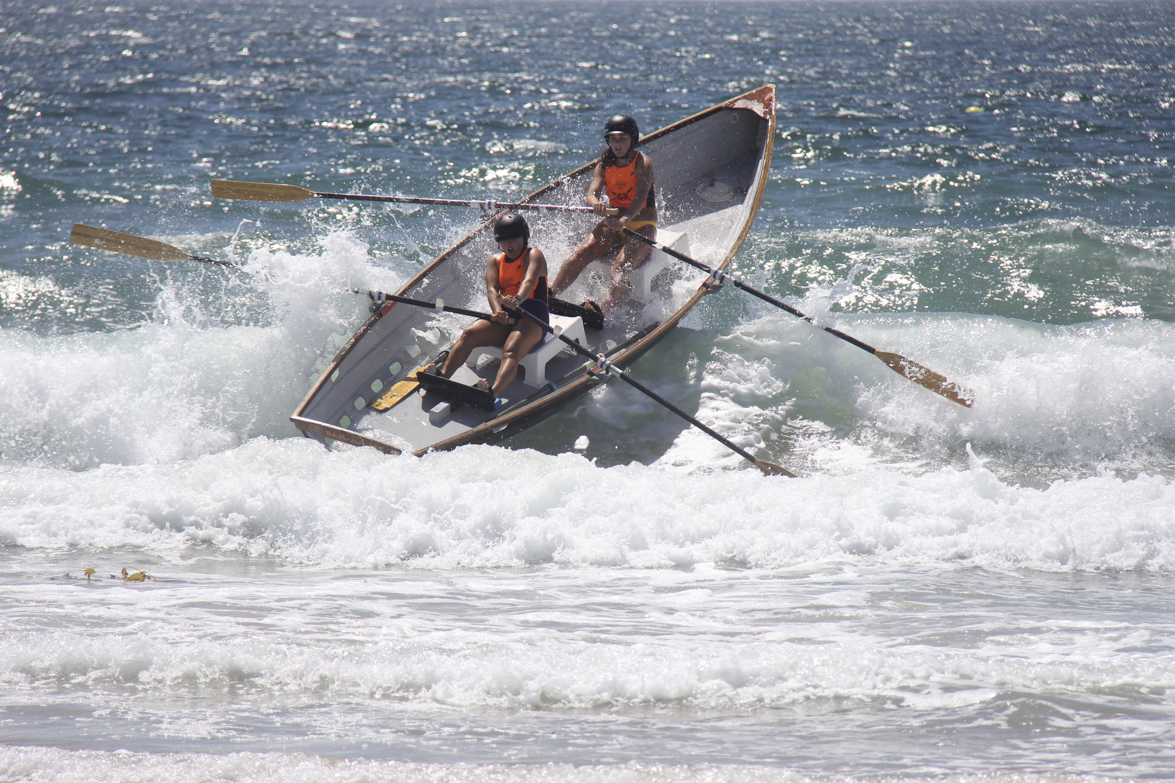 Paige Schaefer and Maura Kane-Seitz hang on while they go over a wave in a surfboat.   NICOLE CASTILLO