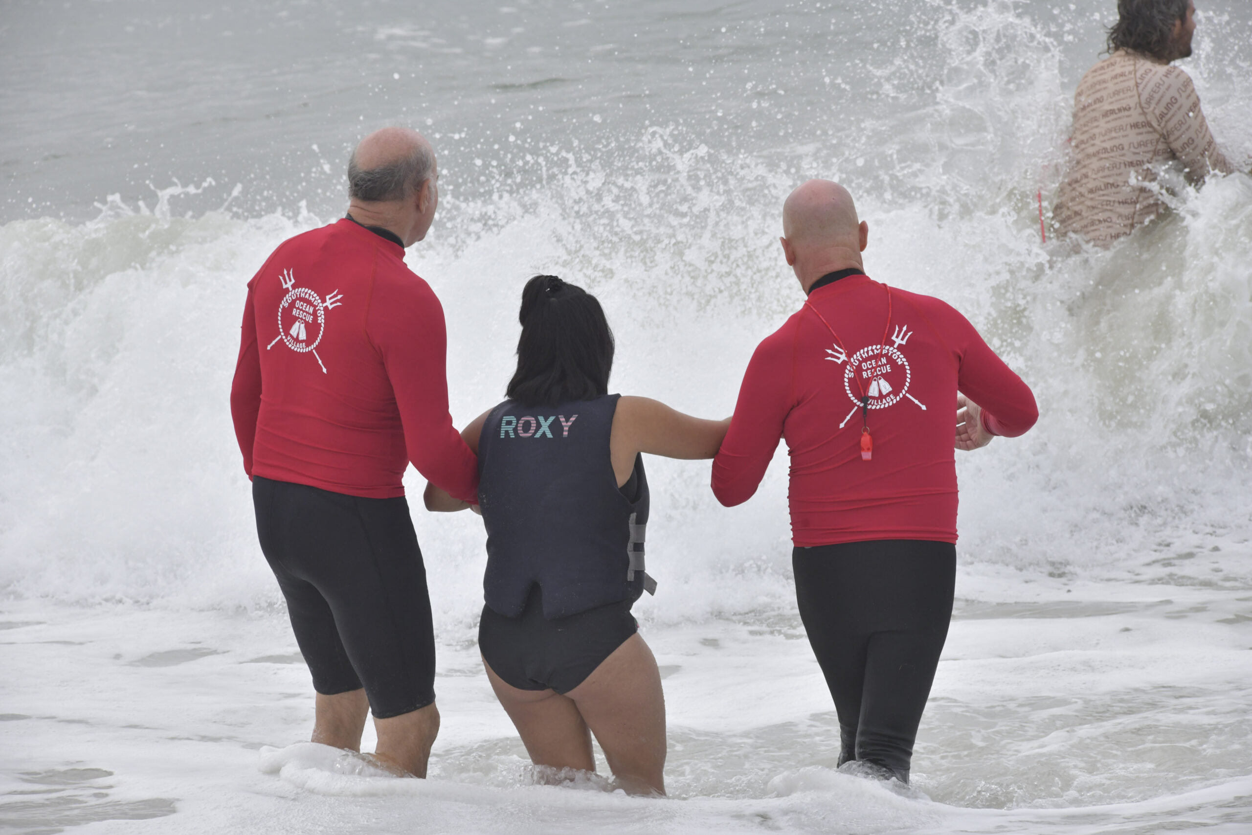 Members of Southampton Village Ocean Rescue help a participant into the water at Surfers for Healing at Ponquogue Beach on September 14.  DANA  SHAW
