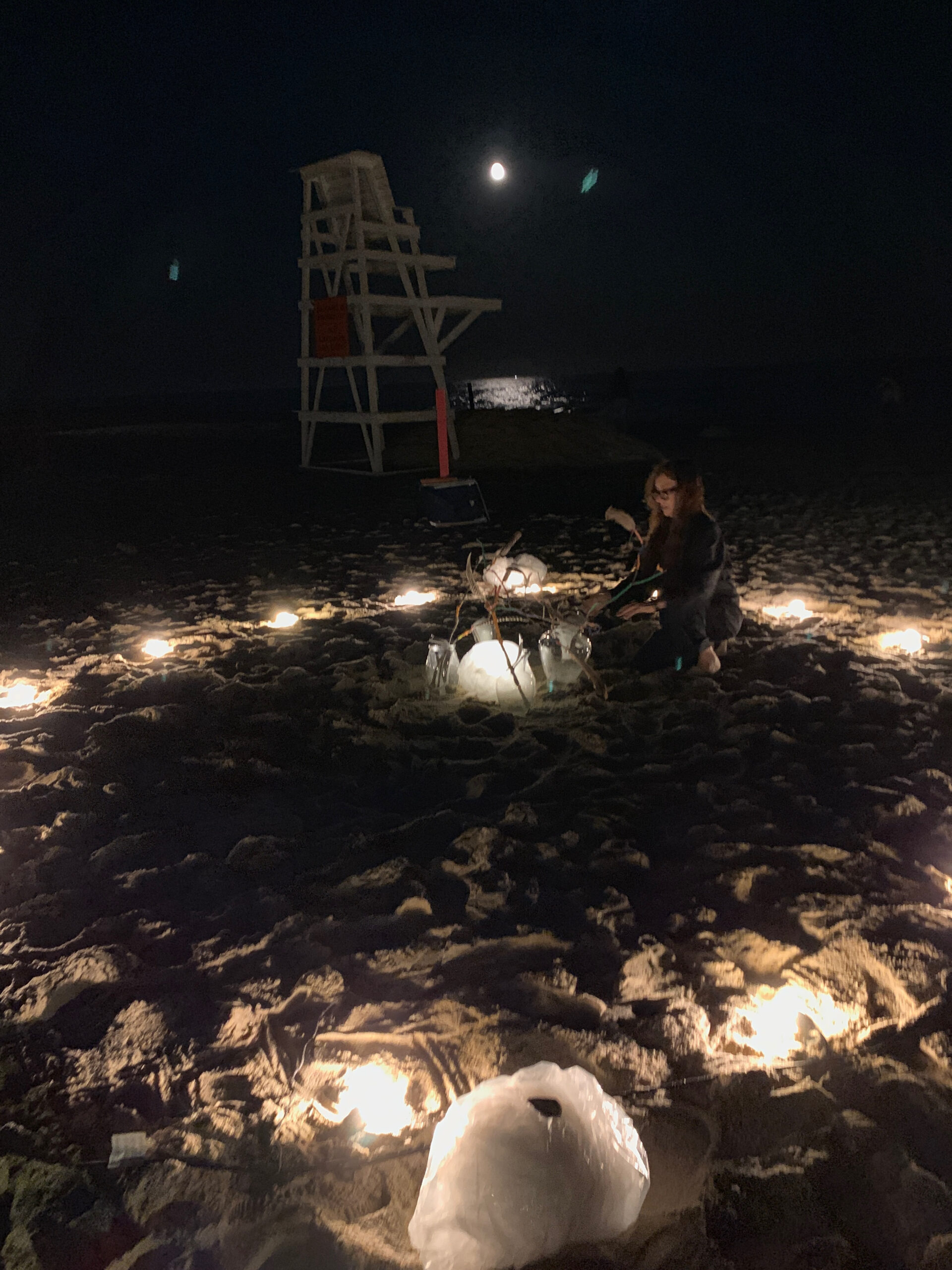 Artist Elana Bajo prepares an art piece under the full moon at East Hampton's Main Beach on September 10 in response  to a musical love letter from West Coast artist Jasmine Orpilla. ANNETTE HINKLE