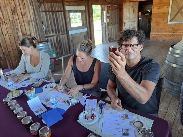 Restaurateur Anthony Martignetti of Broome Street Hospitality examines an entry in the Hallockville Jam and Honey contest during preliminary judging September 2 in the Naugles Barn at Hallockville Museum Farm. Final judging and winner selection will take place on September 18 at the 41st Hallockville Country Fair. Also pictured are Marissa Drago, left, owner Main Rd. Biscuit Co., Jamesport; and Angela Ledgewood. COURTESY HALLOCKVILLE MUSEUM FARM