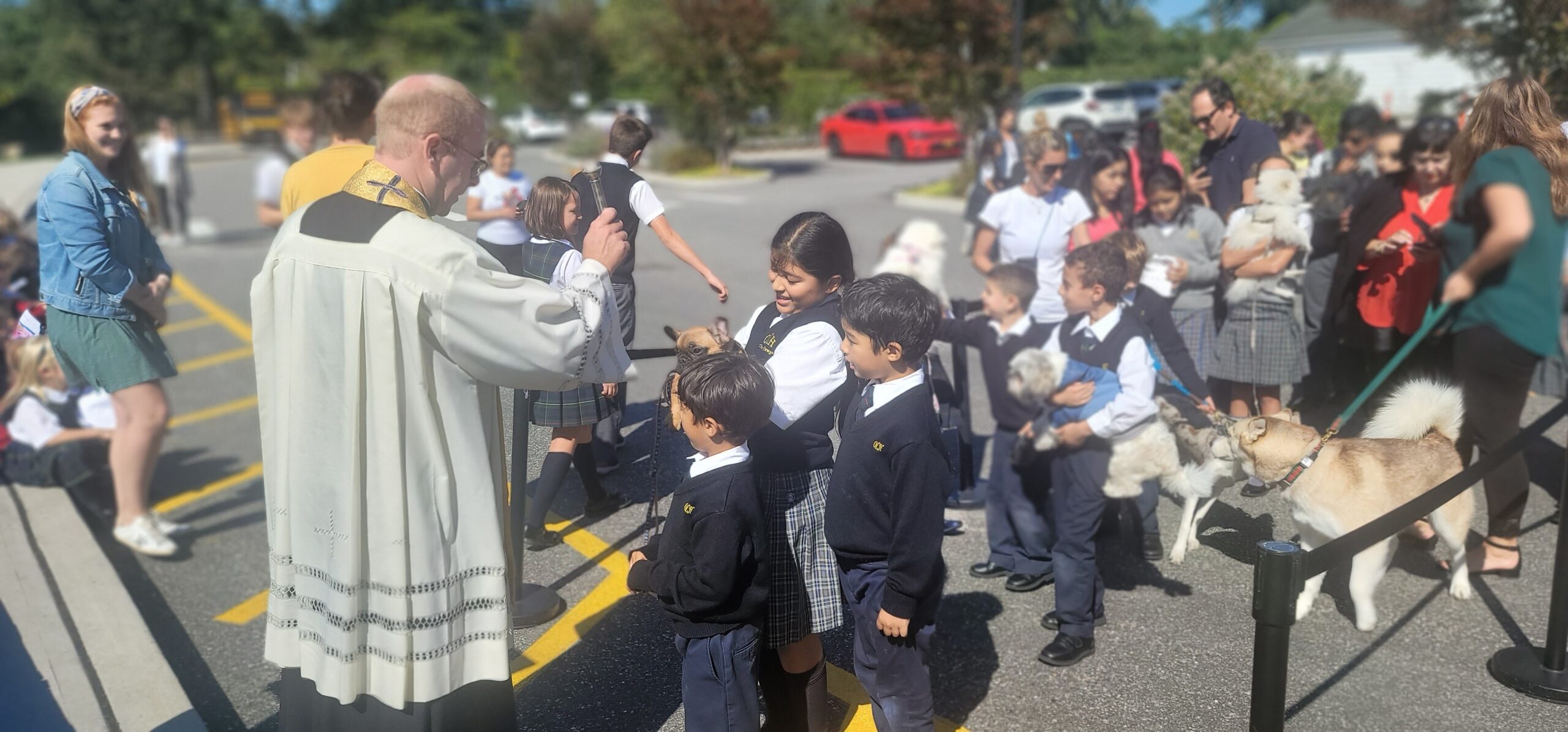 Father Ryan Creamer blesses the pets of the Torres family at the Our Lady of the Hamptons School's Blessing of the Animals last week. COURTESY OUR LADY OF THE HAMPTONS SCHOOL