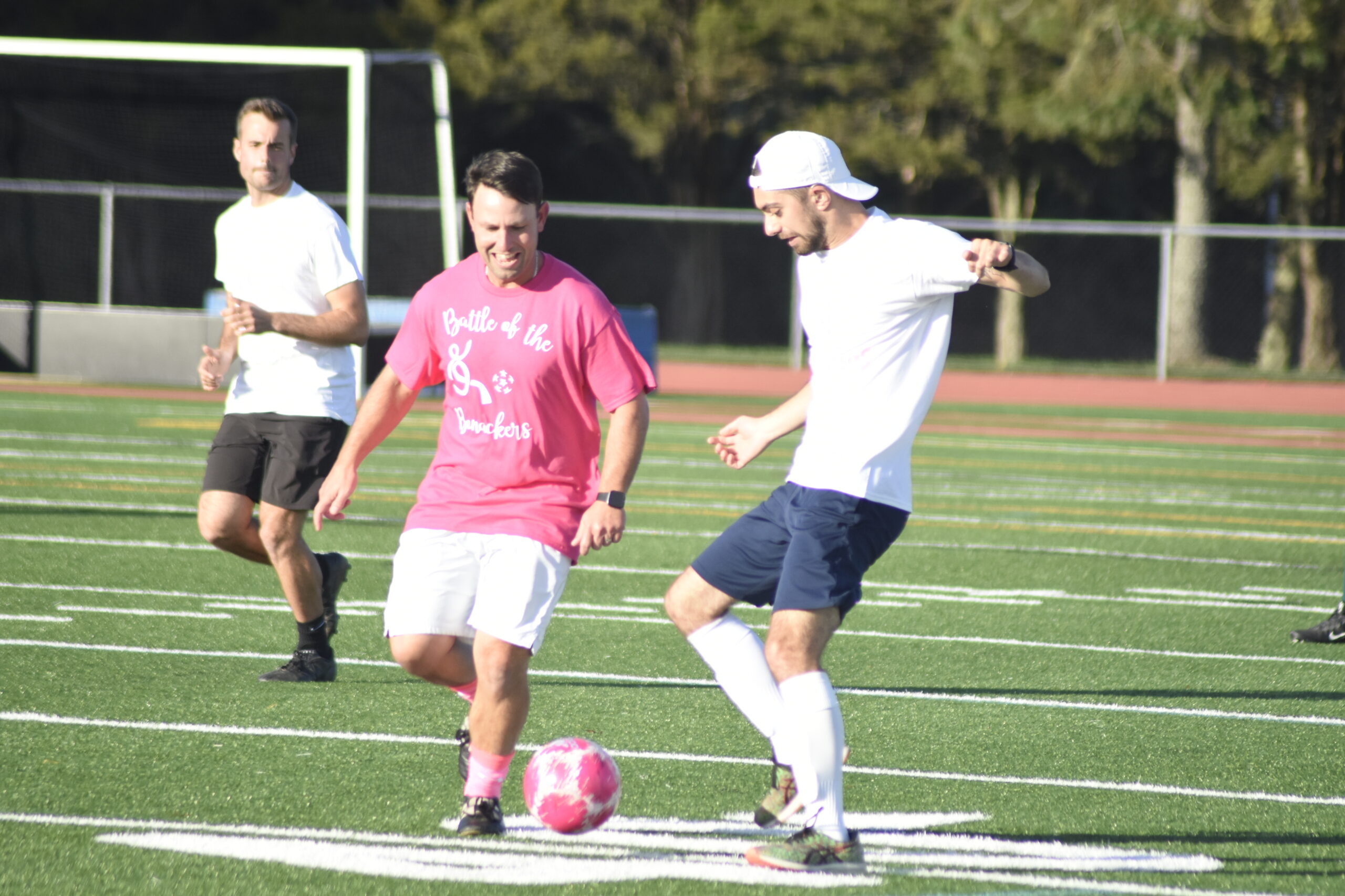 East Hampton boys varsity assistant coach Anthony Roza in the pink and Nicholas DeLuca go after the ball.  DREW BUDD