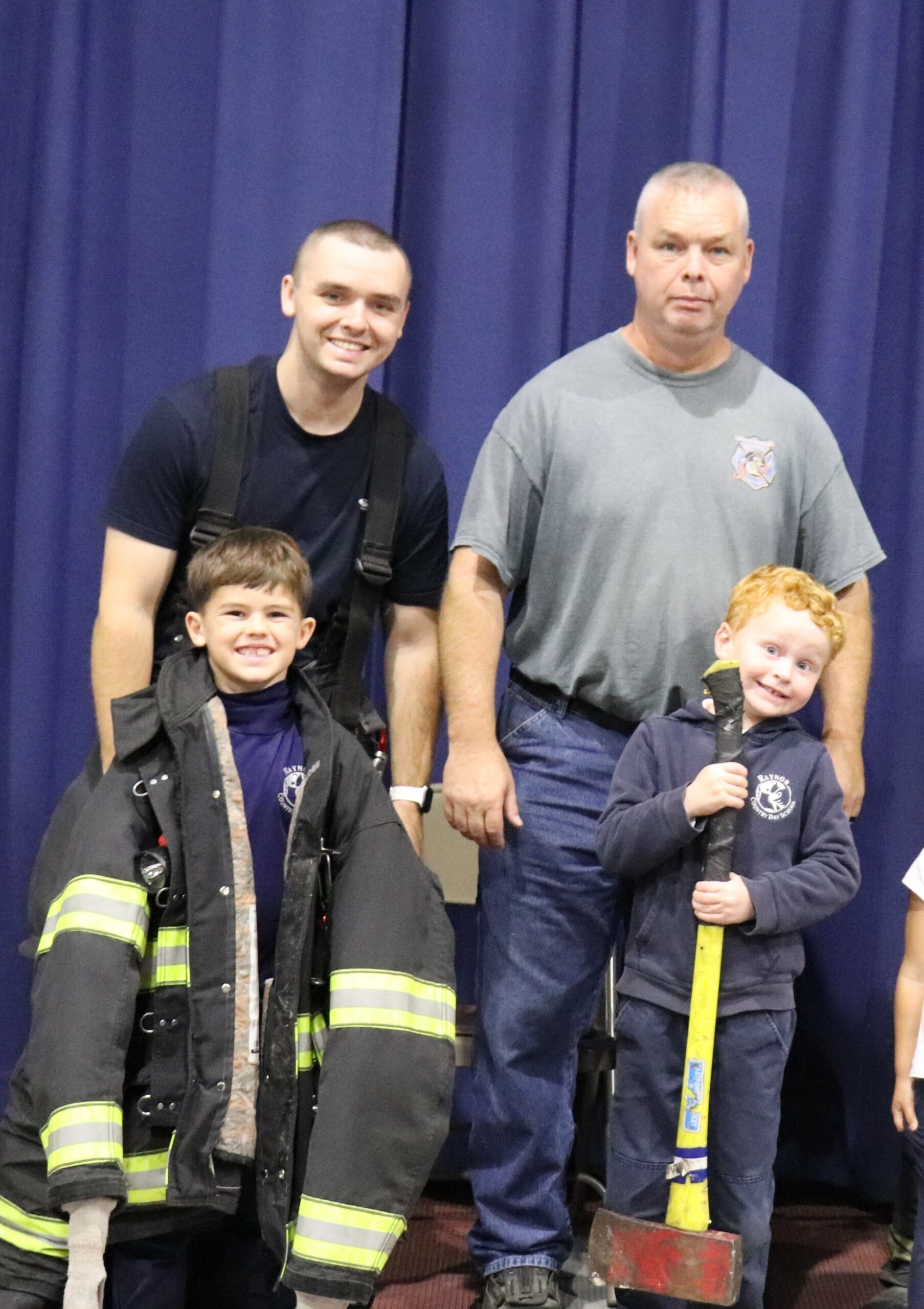 The Eastport Fire Department visited Raynor Country Day School on October 22 to talk about fire safety and the new equipment the department has in its fleet. James Burkley and James Sullivan take a turn with some firefighting equipment with the assistance of a volunteer firefighter.  COURTESY RAYNOR COUNTRY DAY SCHOOL