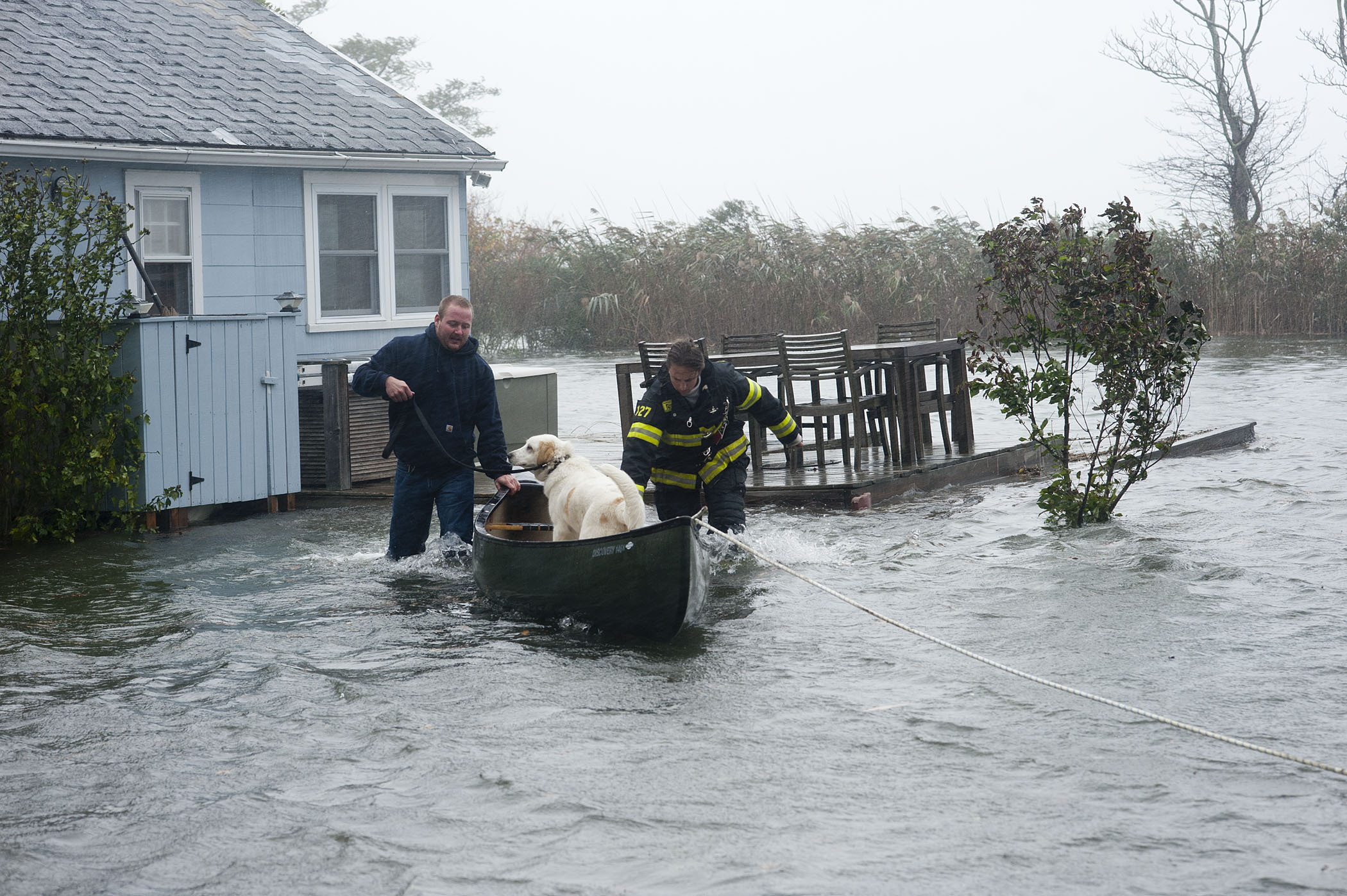 At roughly 11:00 a.m., Sag Harbor Firefighters Mike Labrozzi and Kelly Bailey use a canoe to transport a pet dog as they help rescue a Bay Avenue, Pine Neck resident and his pets who had become stranded due to rising water during hurricane Sandy on Monday, October 29, 2012.   MICHAEL HELLER